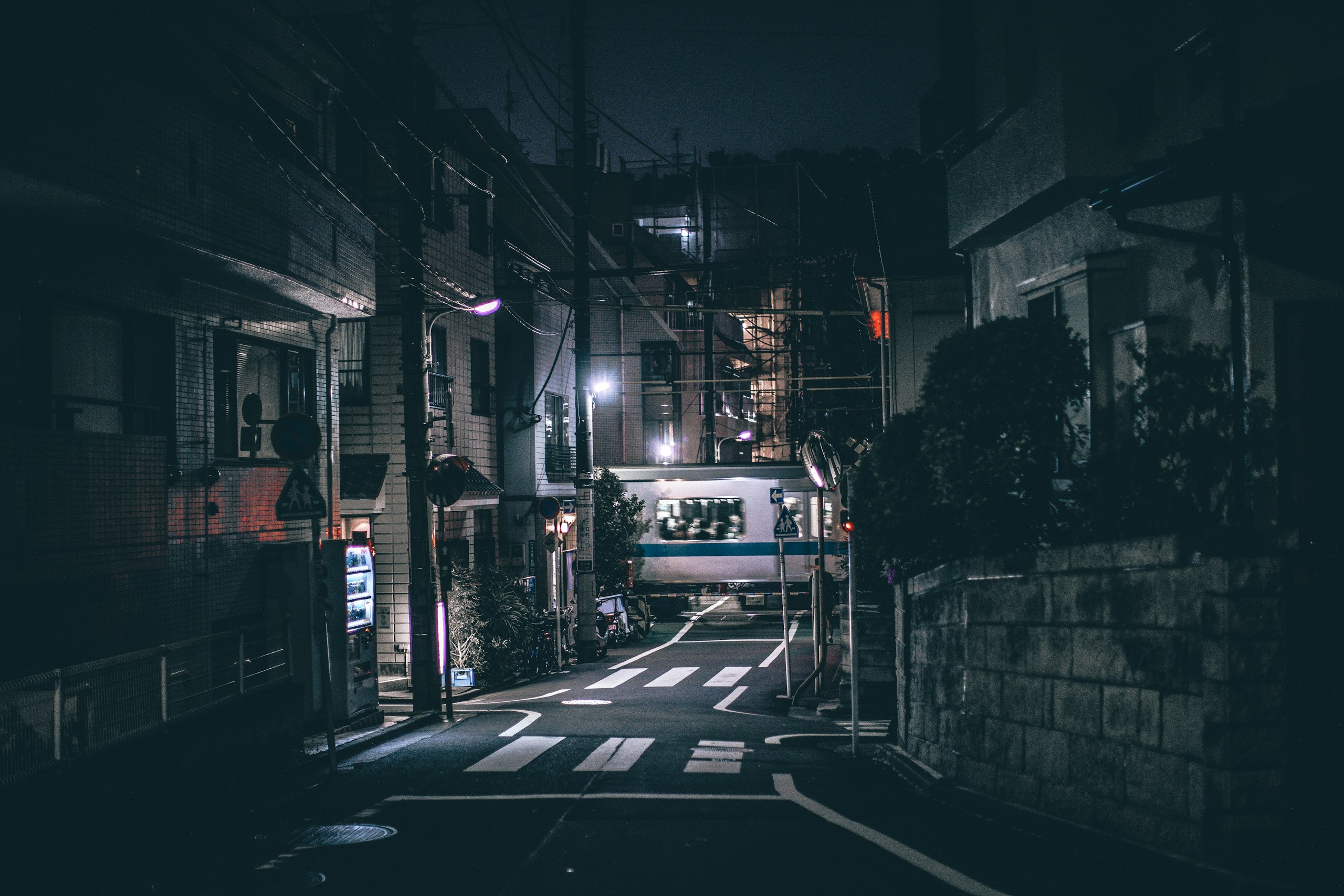 Narrow Japanese street at night with a passing train HD Wallpaper