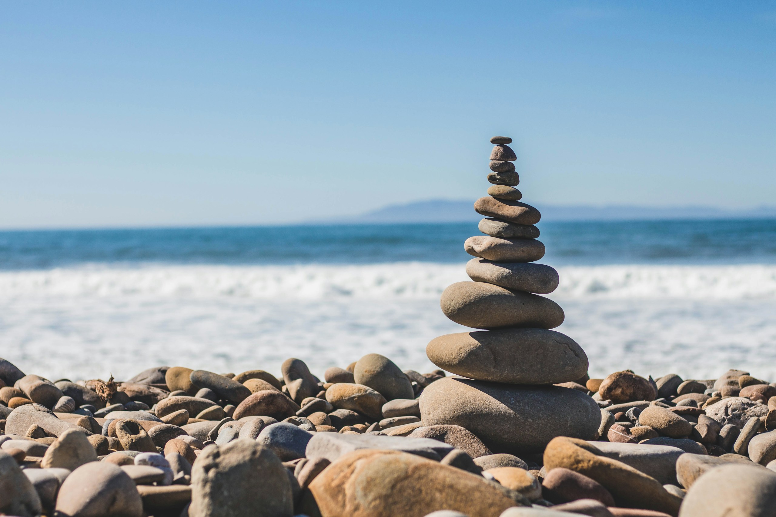 Balanced pebble tower on a rocky beach HD Wallpaper