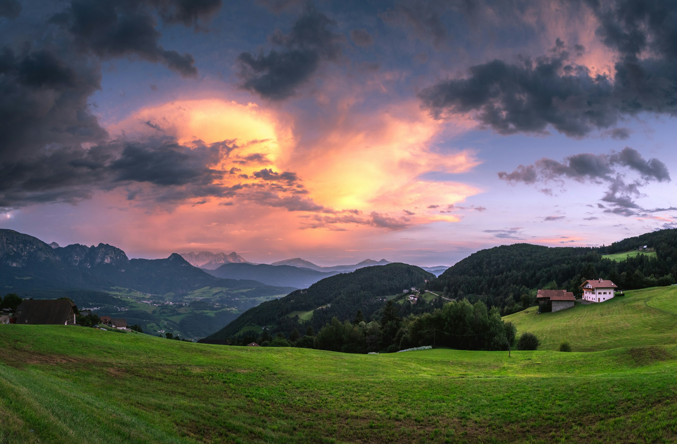 Sunset over rolling green hills and distant mountains HD Wallpaper