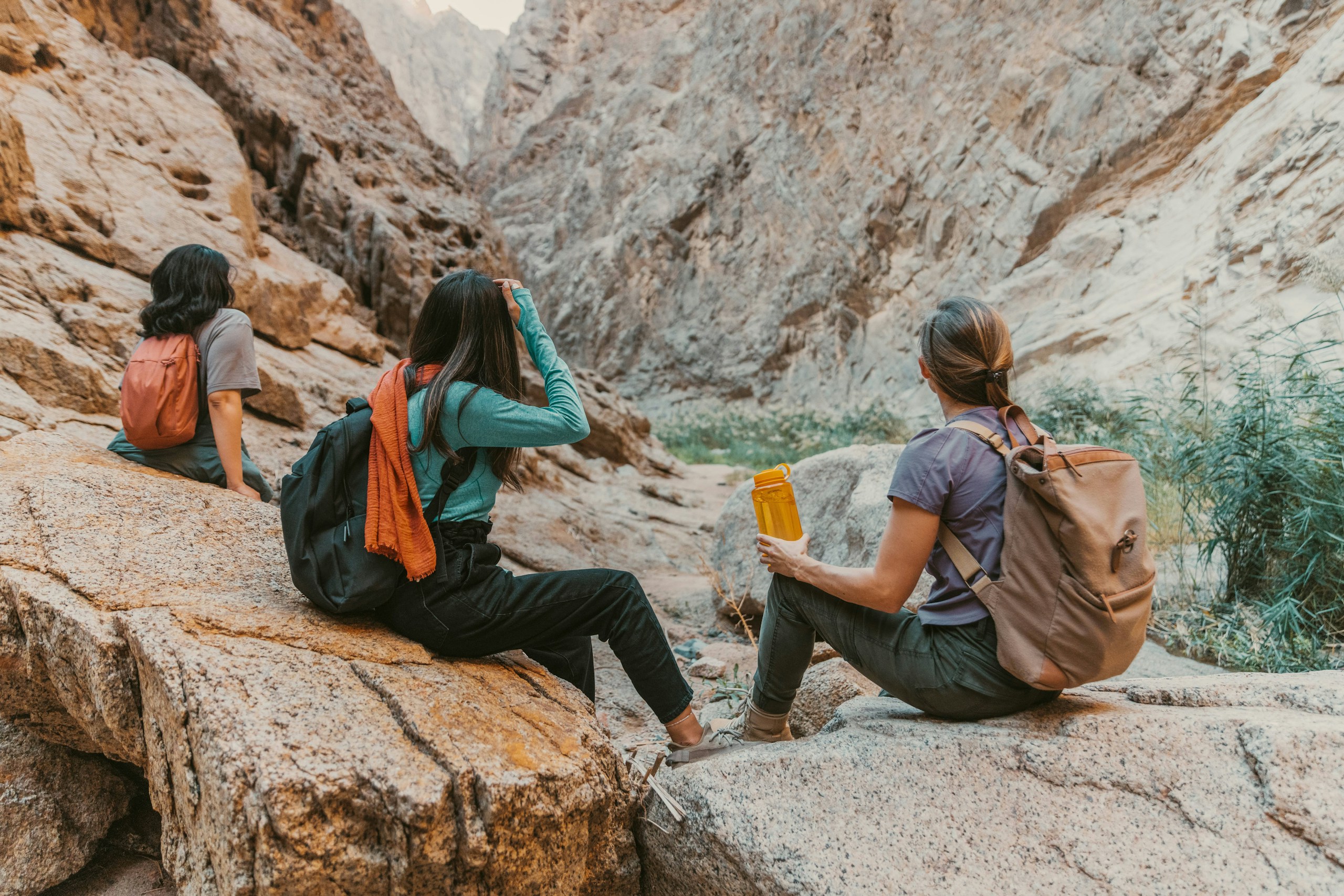 Three women hikers resting in a rocky canyon HD Wallpaper
