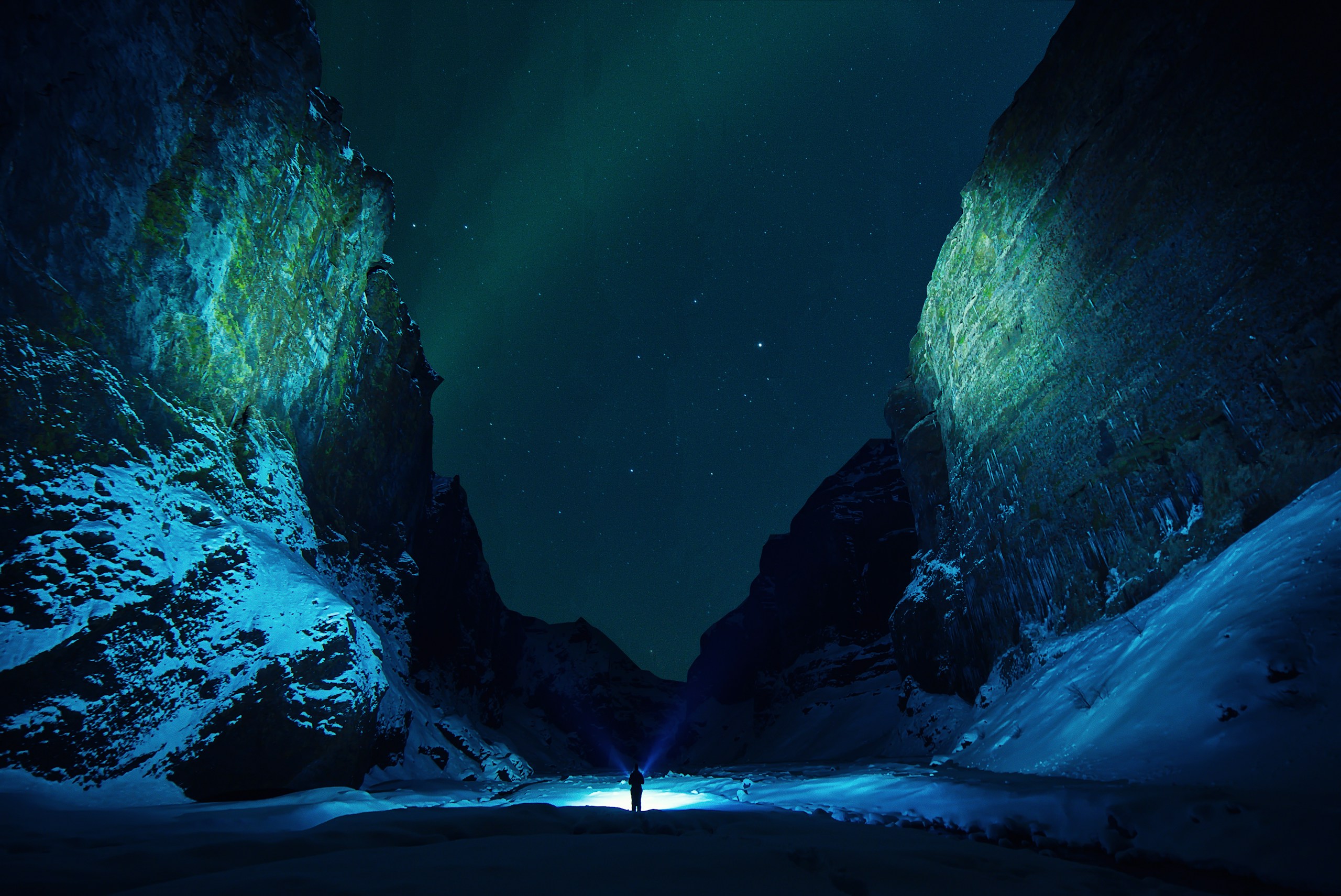 Person with flashlight in a snowy canyon at night HD Wallpaper