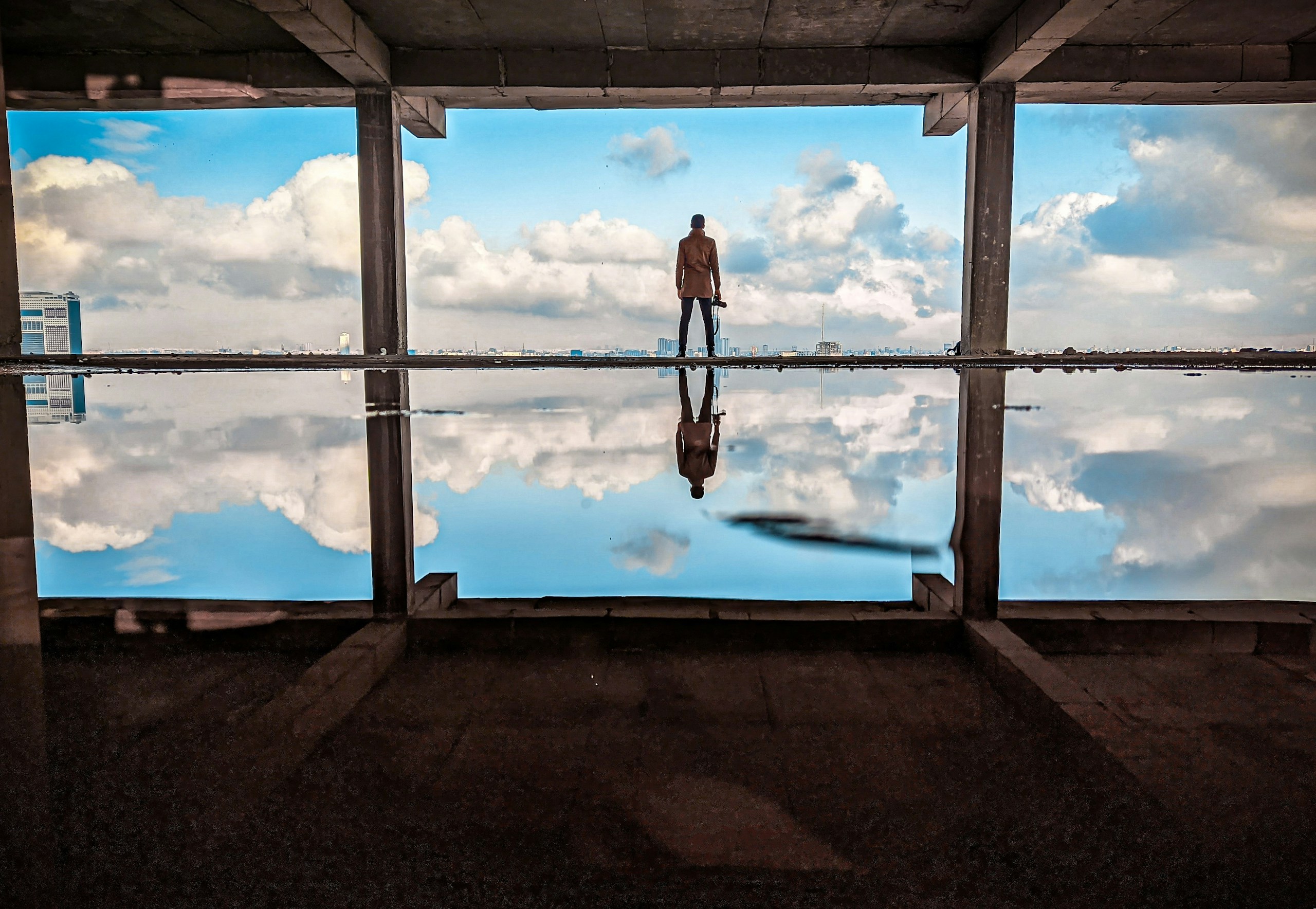 Man standing in unfinished building with water reflection HD Wallpaper