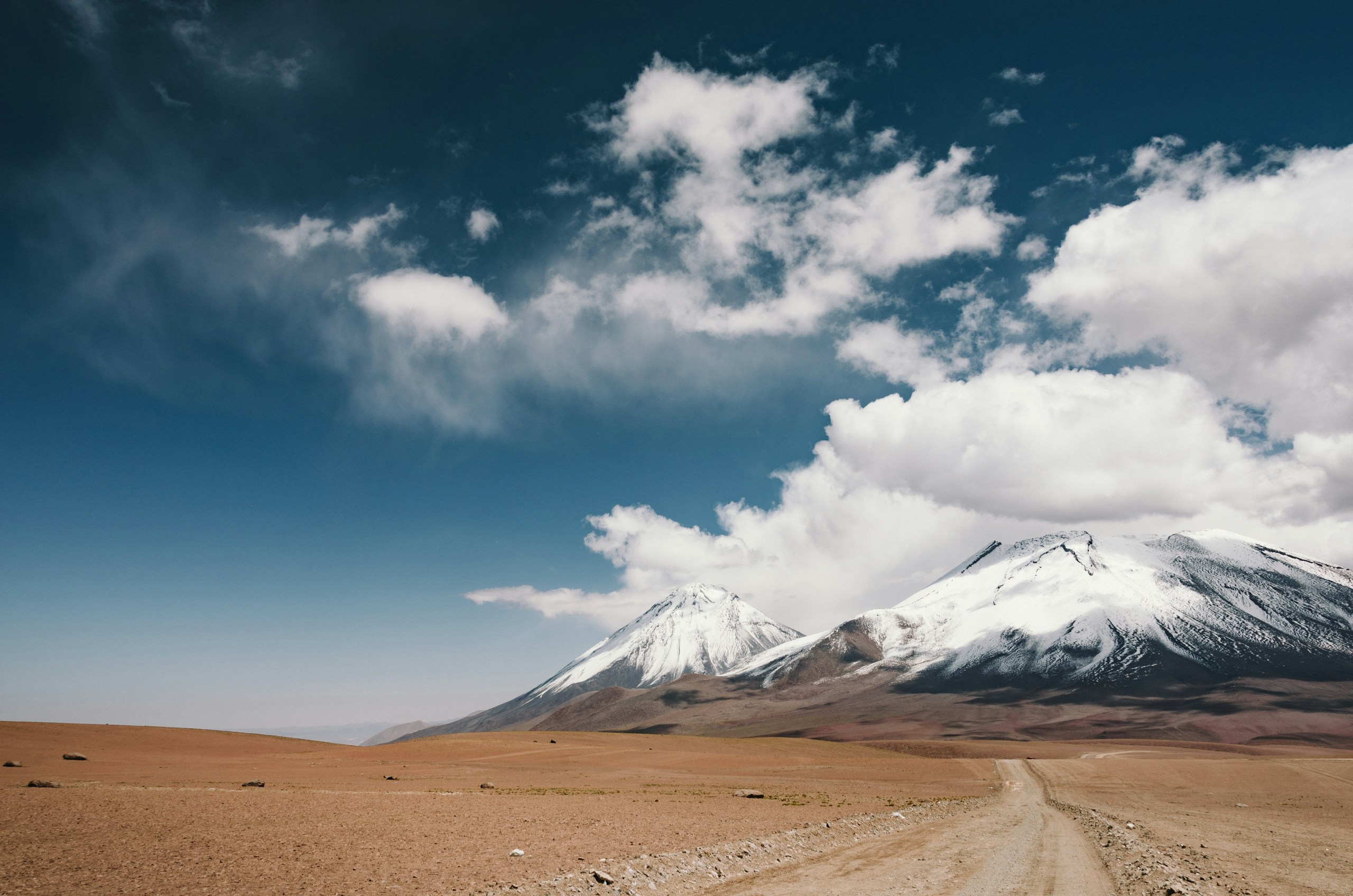 Snow-capped Licancabur volcano in the desert HD Wallpaper