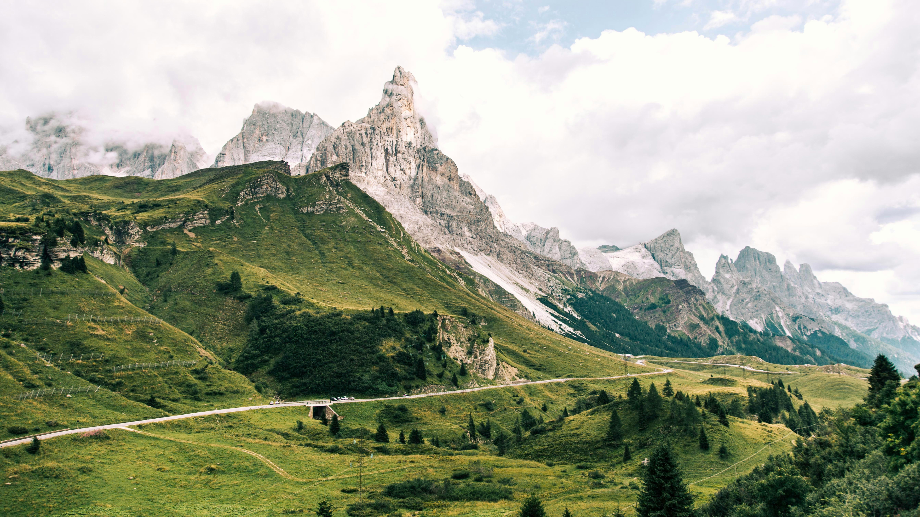 Winding Road Through Green Hills and Rocky Mountains HD Wallpaper