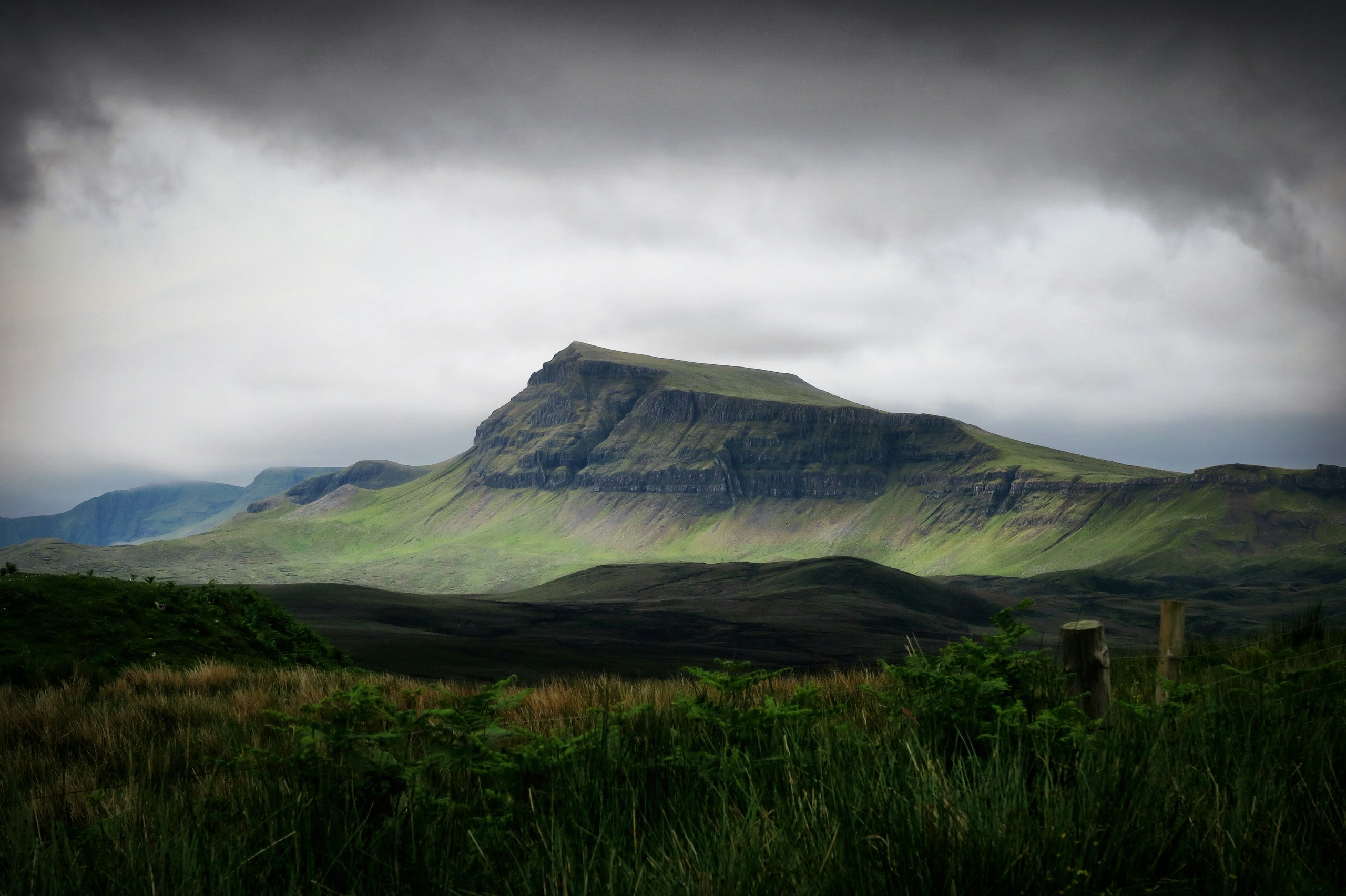 Green mountain under a dark cloudy sky HD Wallpaper