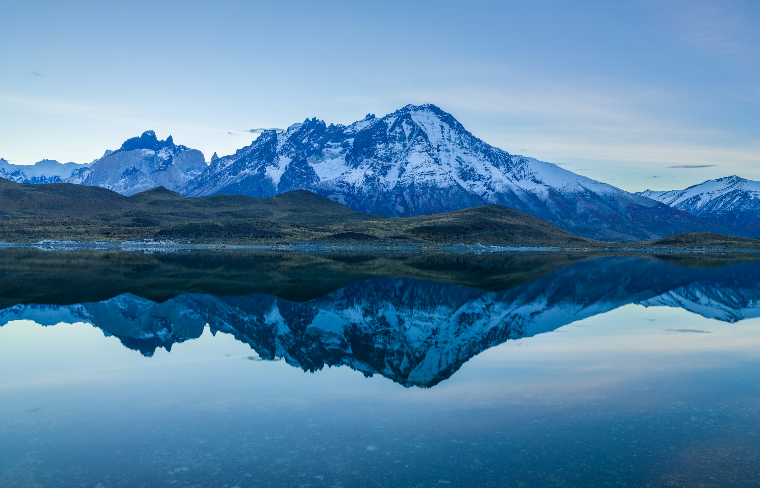 Paine mountain range reflecting in a calm lake HD Wallpaper