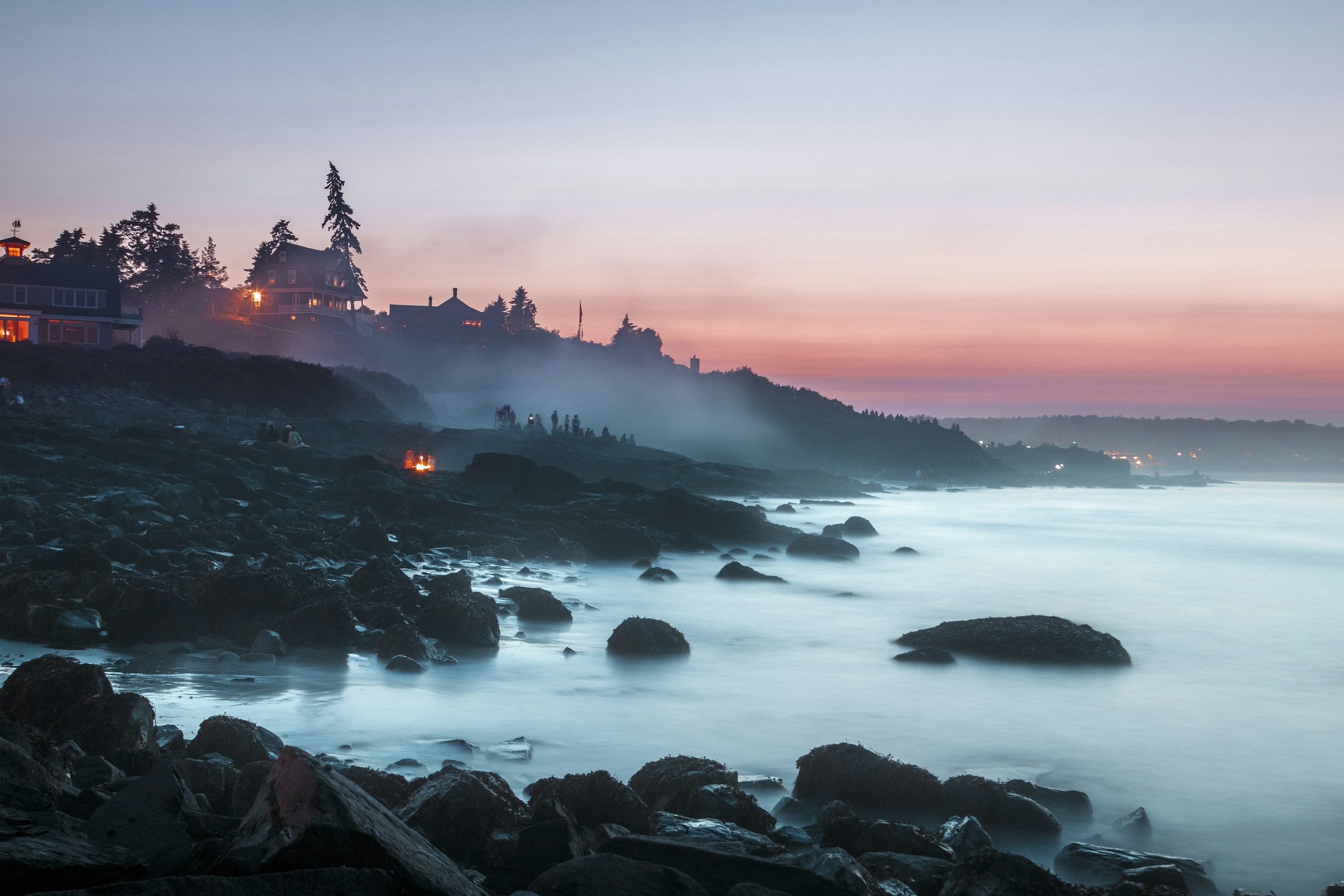 Misty Rocky Coastline with Houses at Sunset HD Wallpaper
