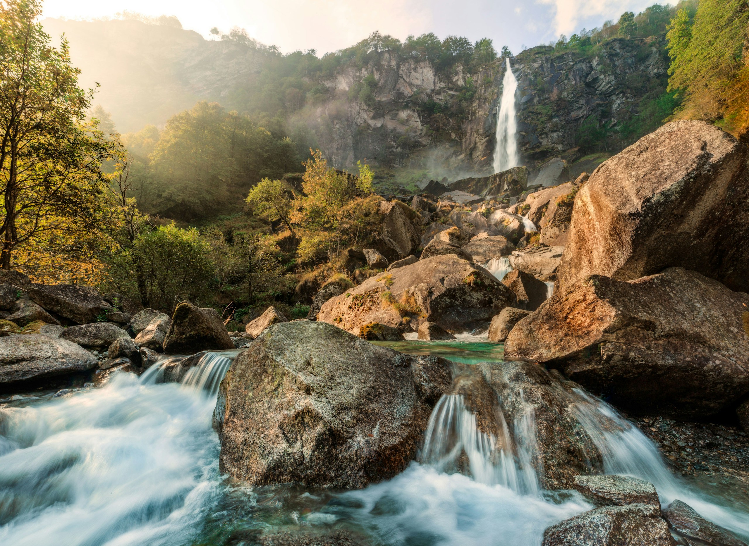 Waterfall cascading over rocks into a rushing stream HD Wallpaper
