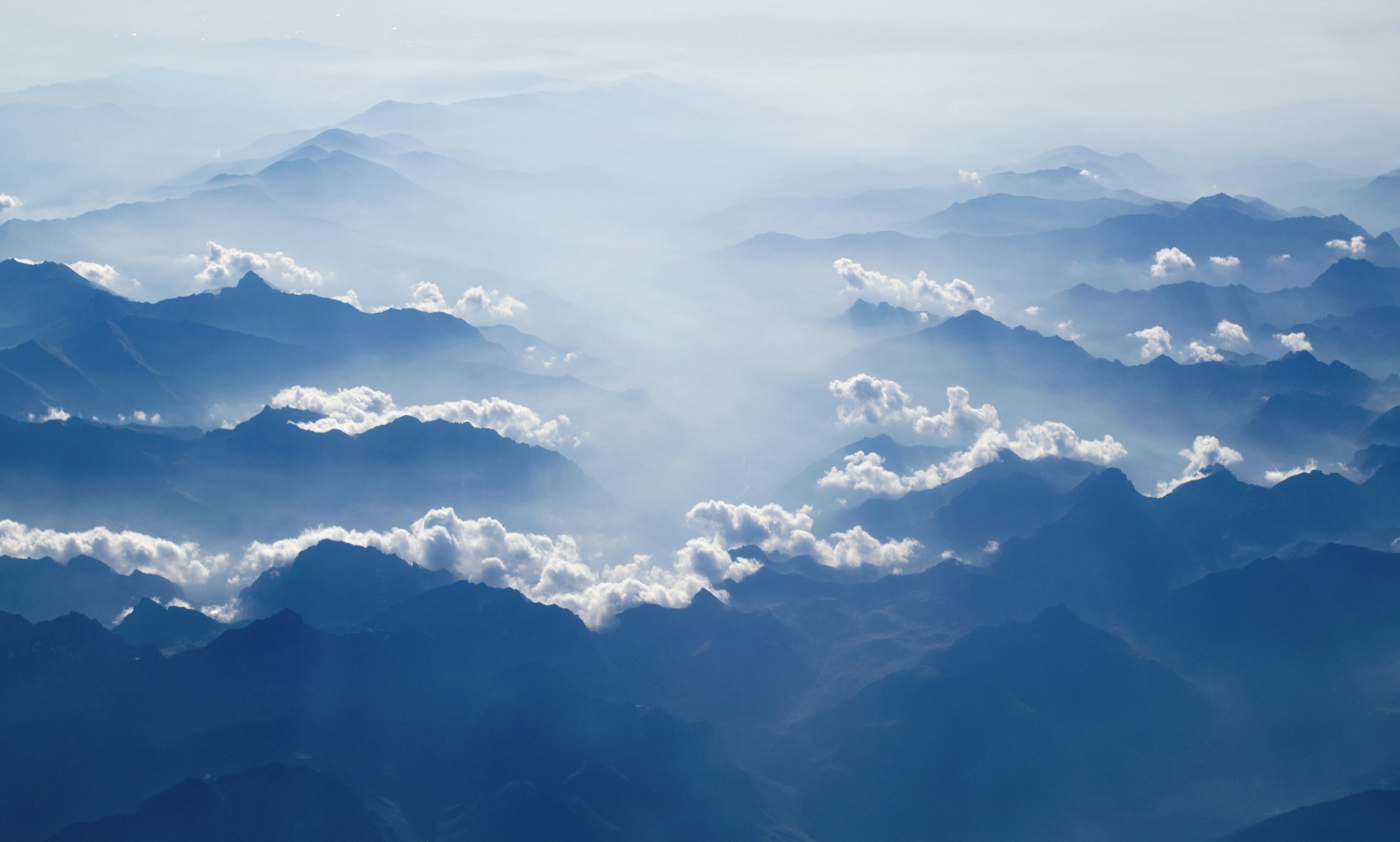 Aerial view of misty blue mountain peaks and clouds HD Wallpaper