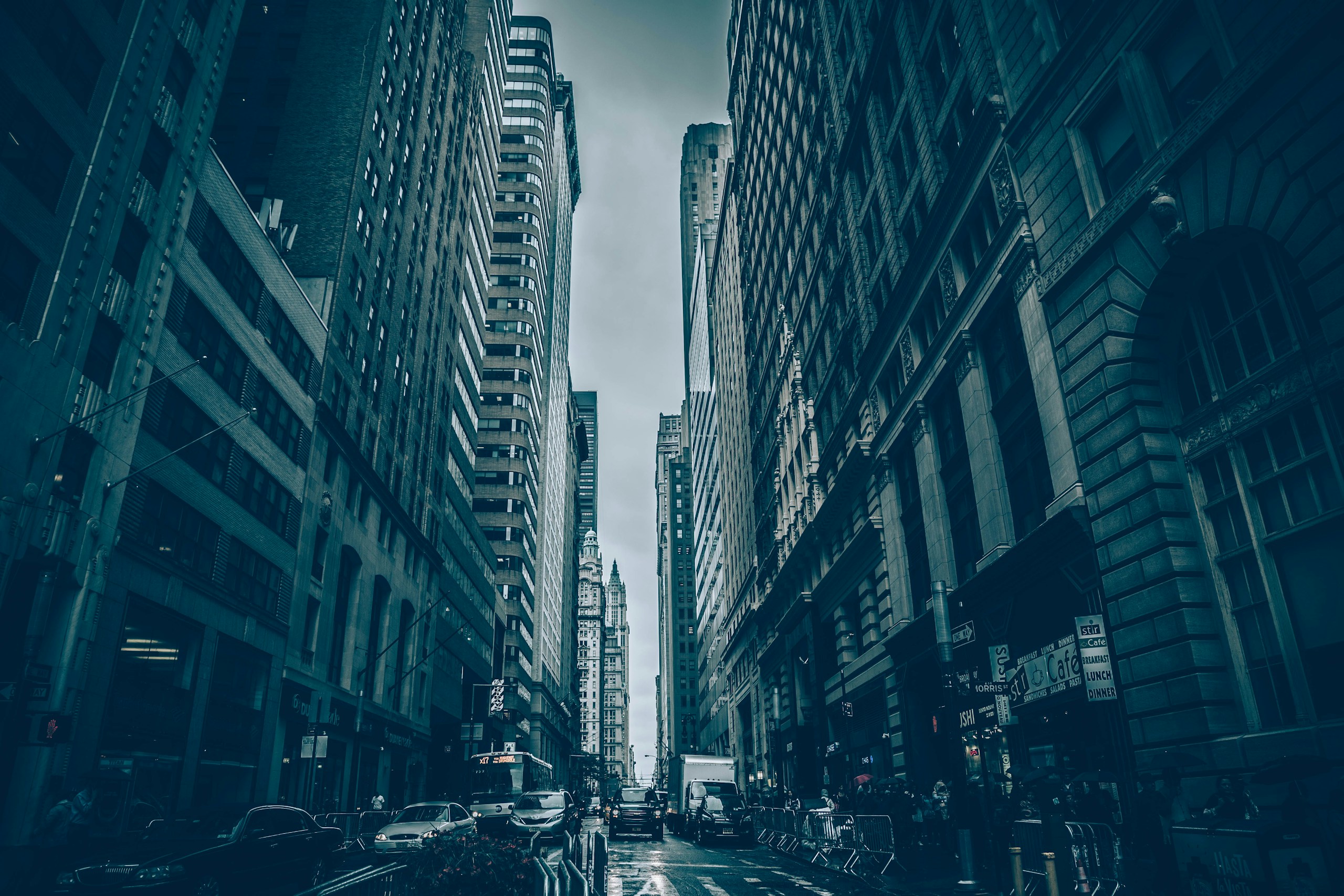 Dark moody city street with towering skyscrapers HD Wallpaper