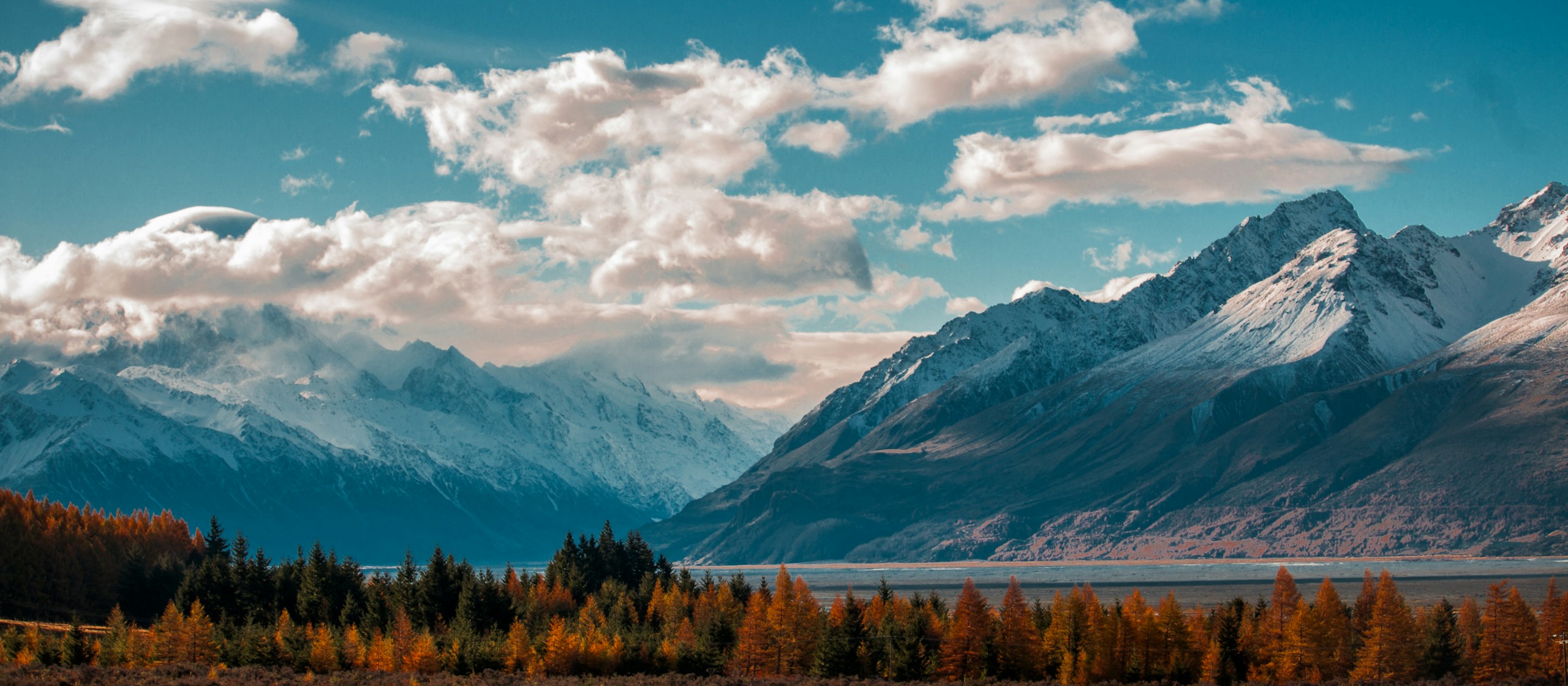 Snow-capped mountains and autumn trees by a lake HD Wallpaper