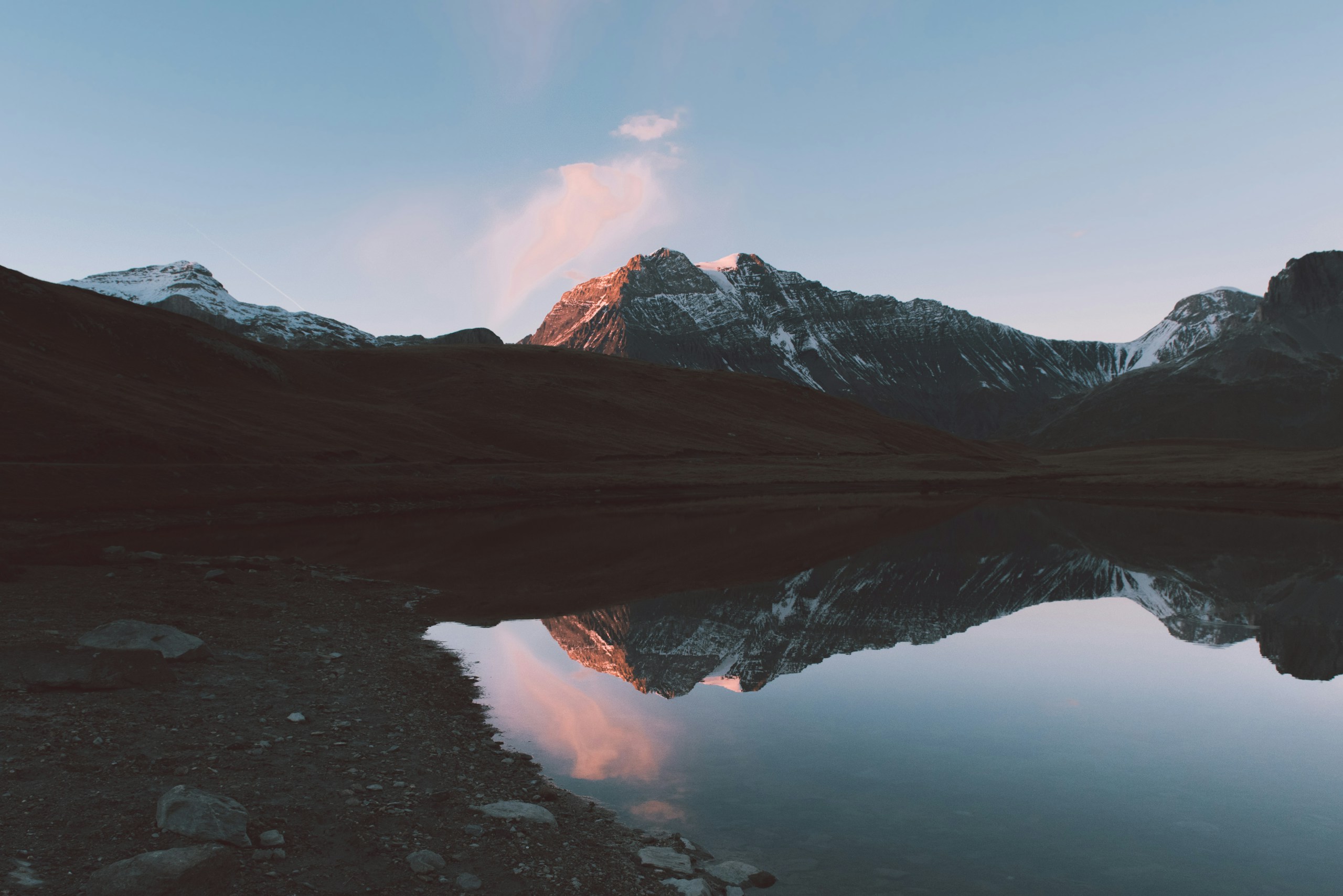 Snowy mountain range reflected in a calm lake HD Wallpaper