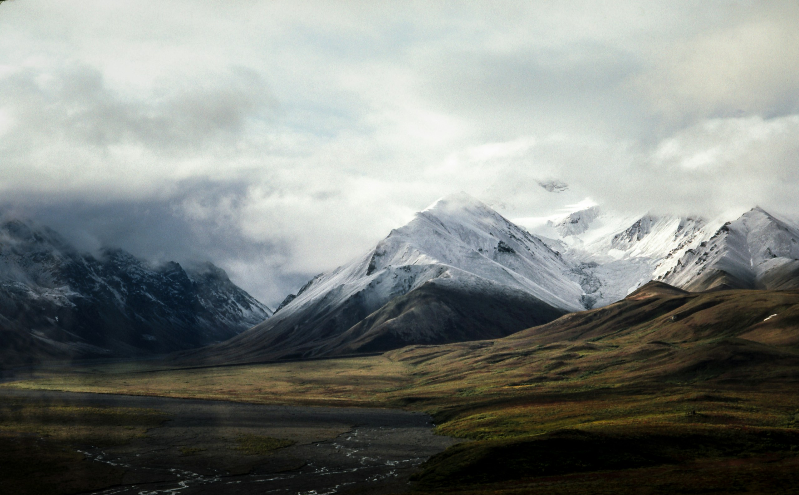Snow-capped mountains and valley under cloudy sky HD Wallpaper