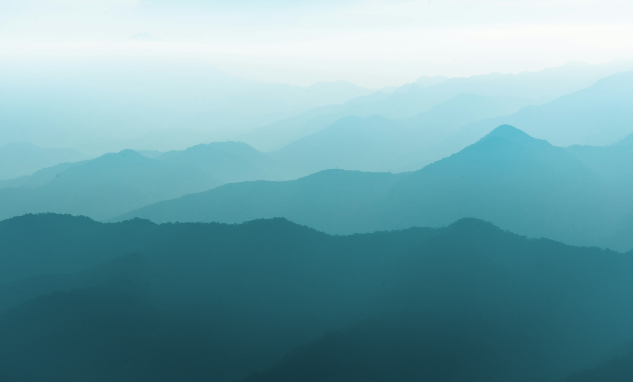 Layered blue mountain ridges in morning mist HD Wallpaper