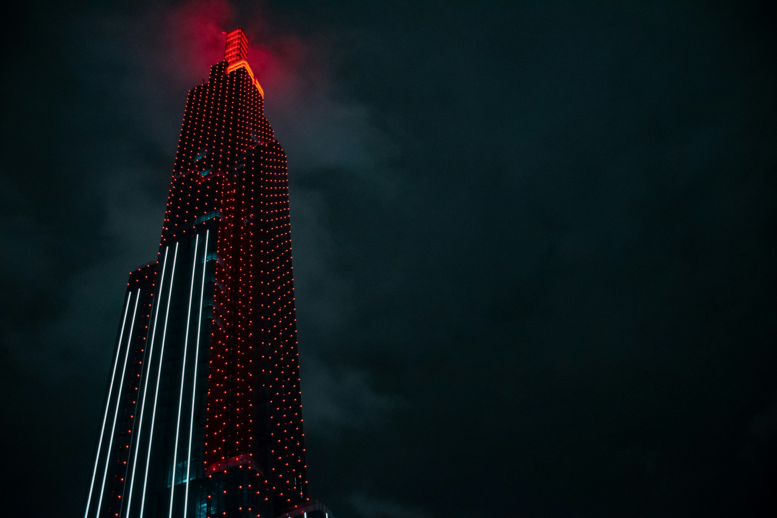 Tall skyscraper illuminated with red lights at night HD Wallpaper