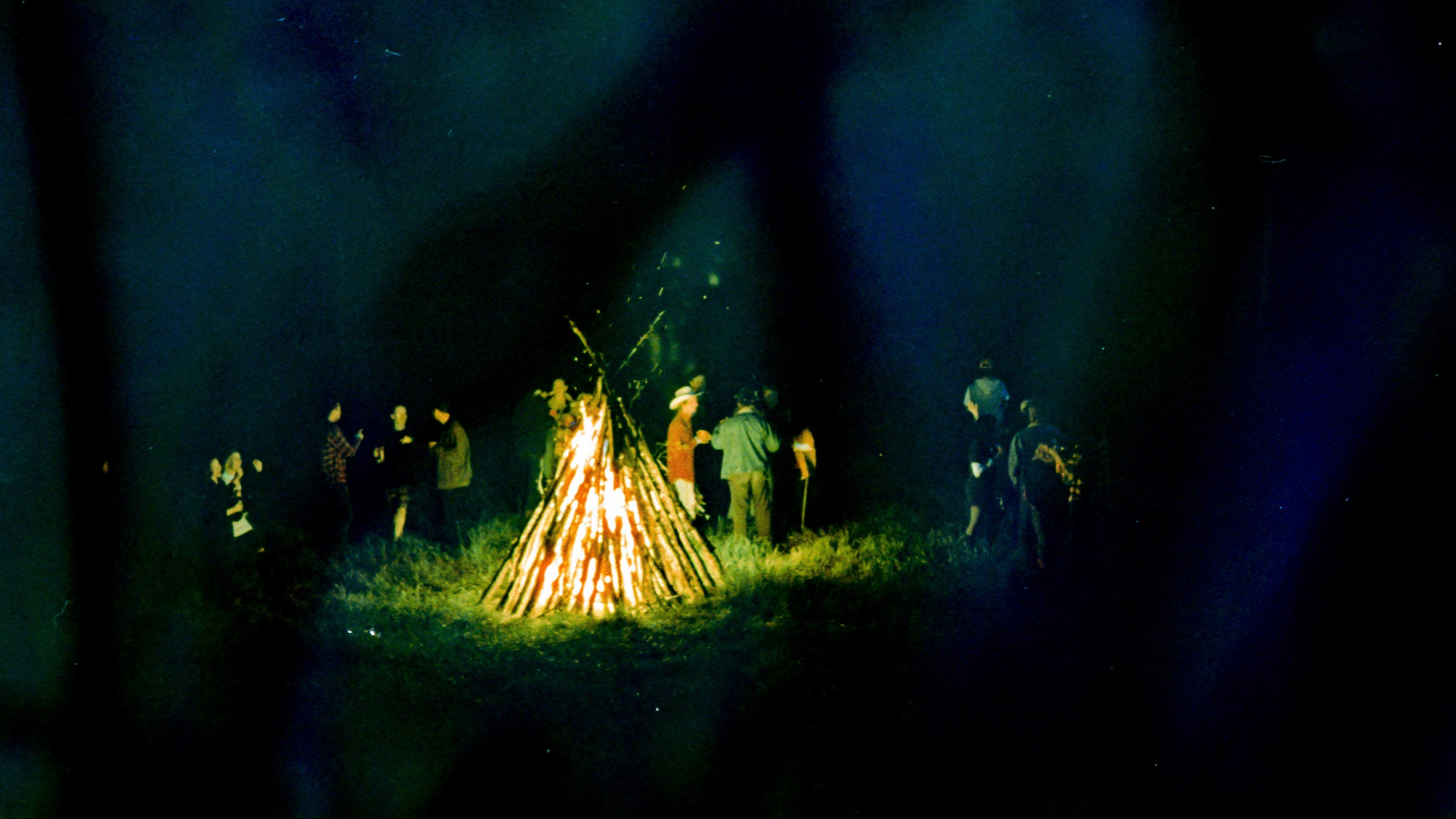 People gathered around a large bonfire in Camp HD Wallpaper