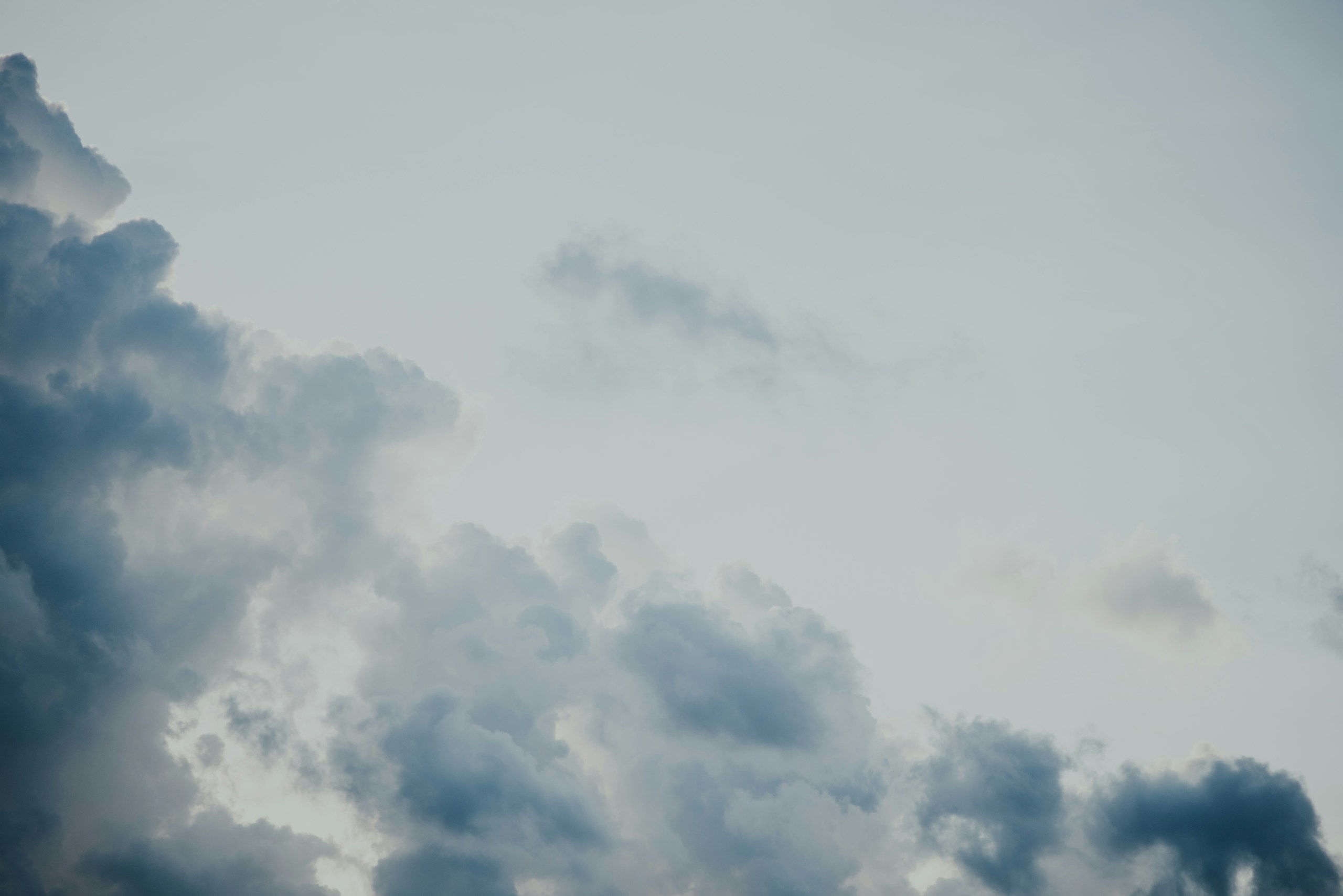 Dark puffy clouds against a pale overcast sky HD Wallpaper