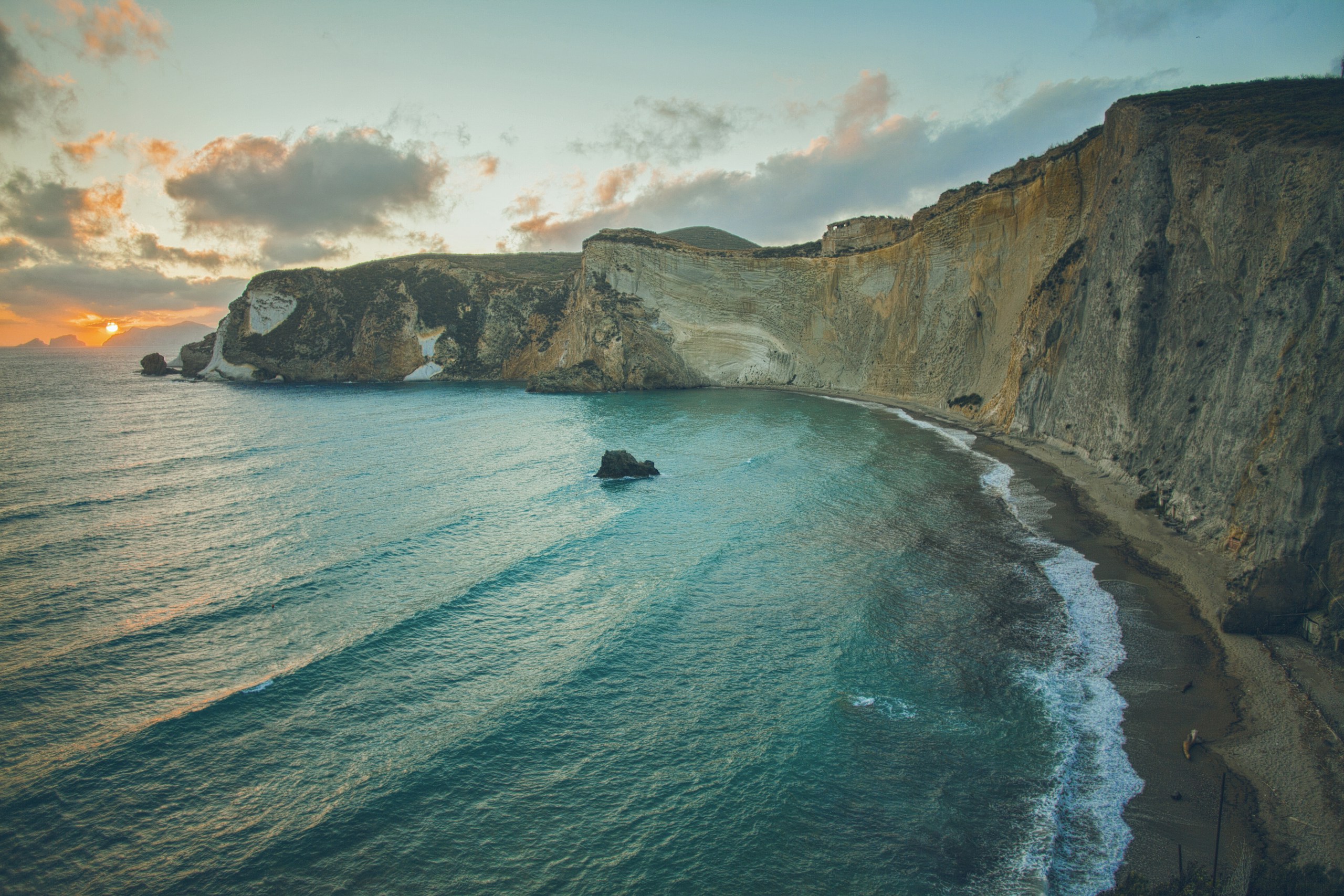 Coastal cliffs and turquoise bay at sunset HD Wallpaper