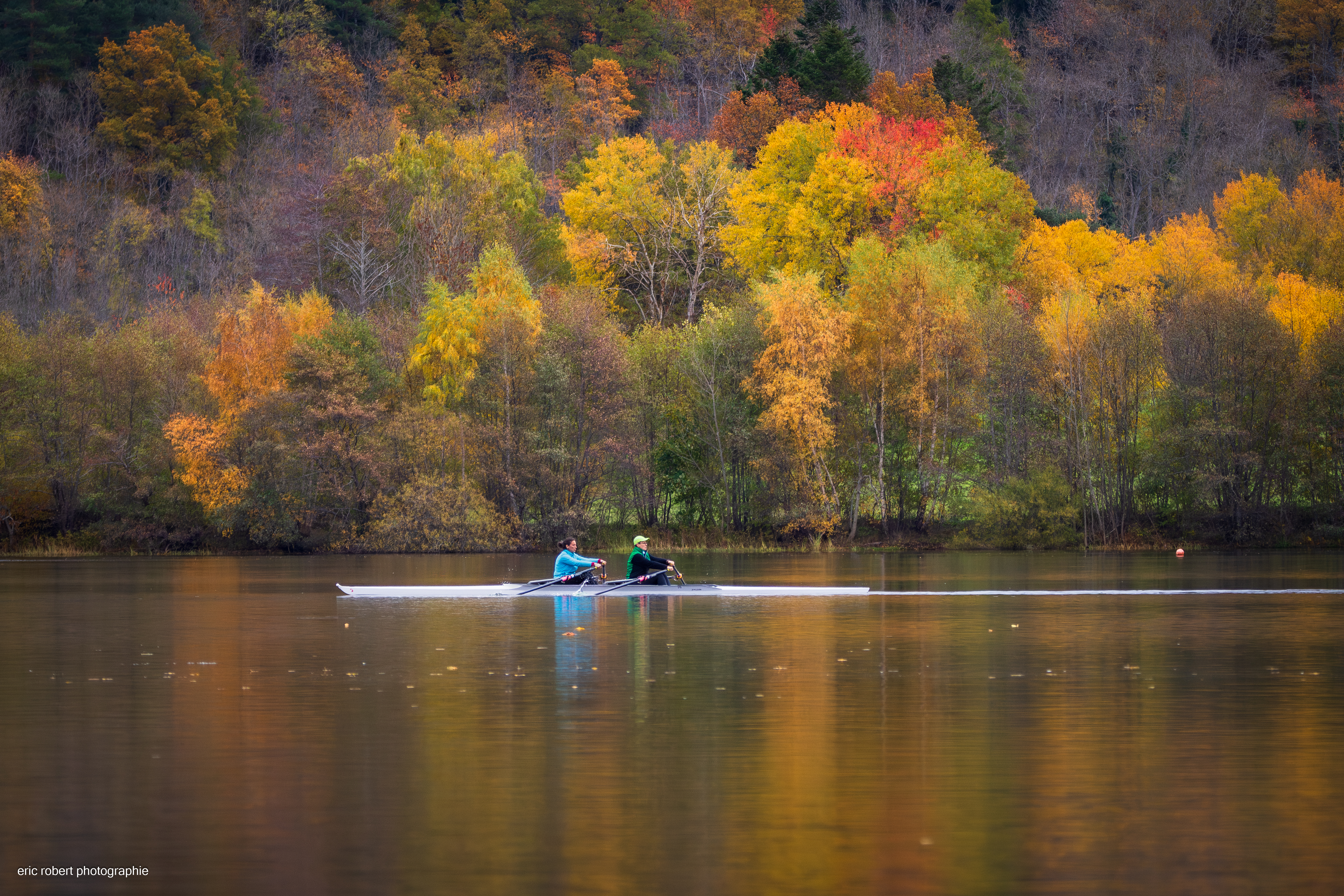 Two people rowing on a calm lake in autumn HD Wallpaper