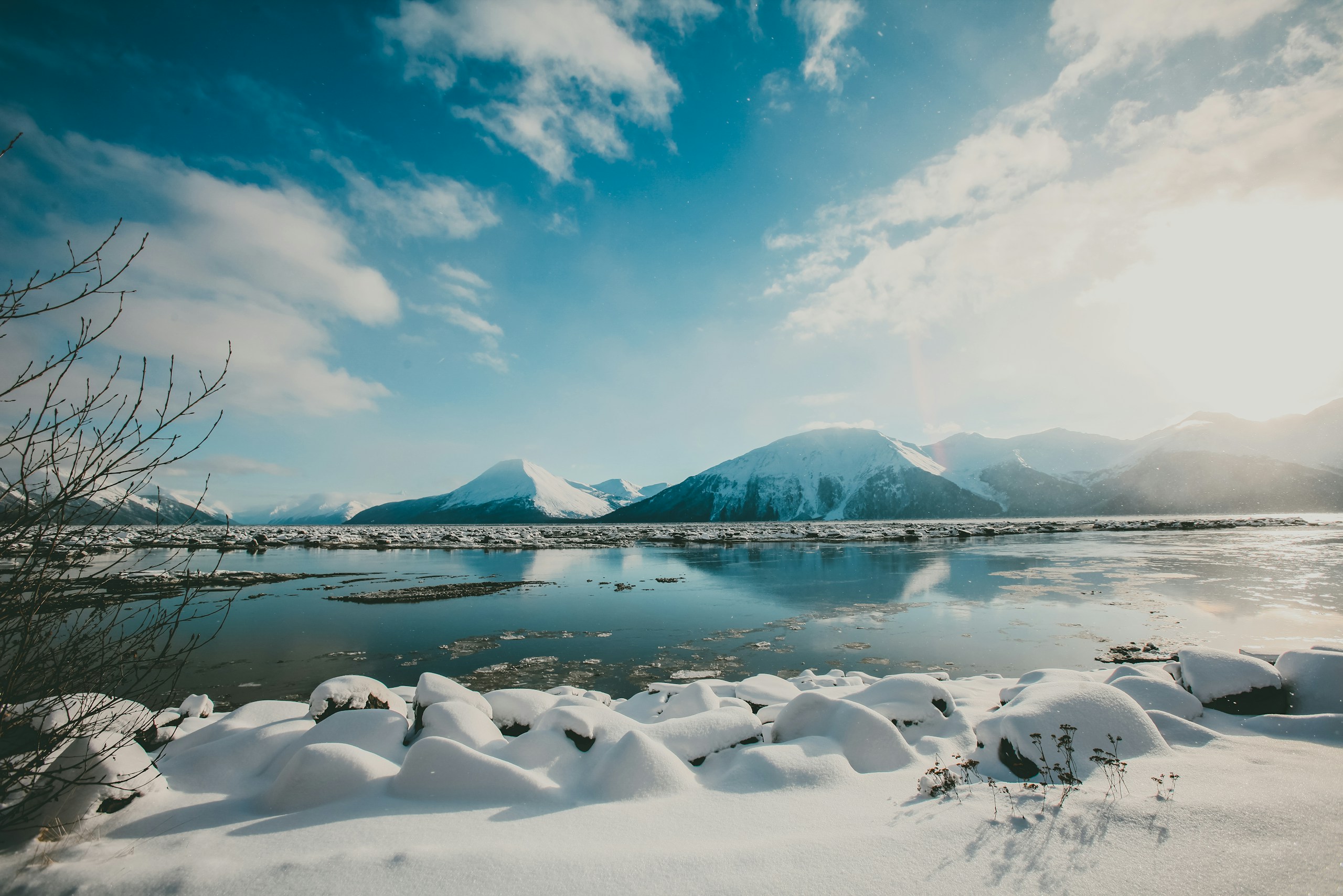 Snow-covered mountains reflecting in calm winter water HD Wallpaper