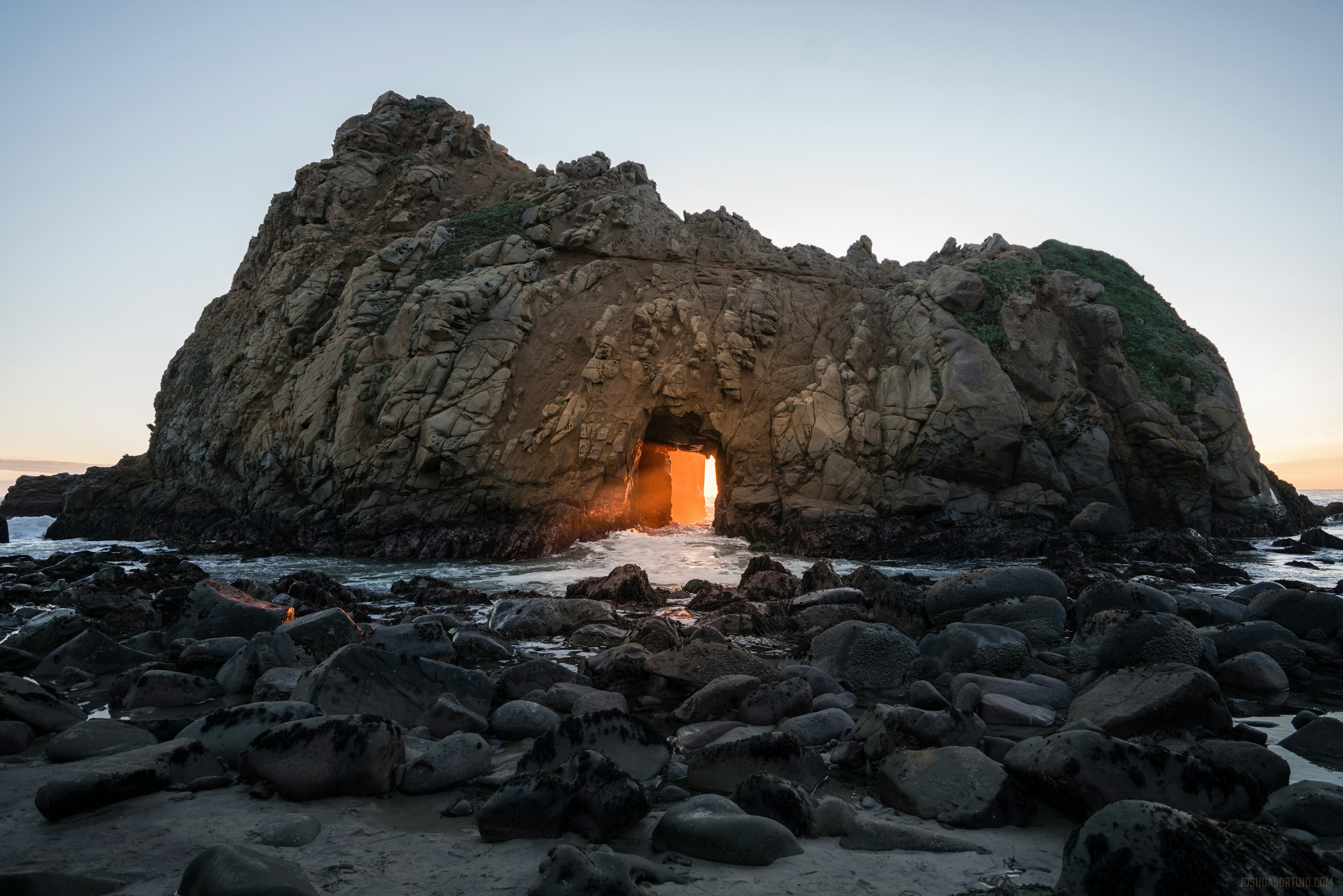 Sunset light shining through Keyhole Arch at Pfeiffer Beach HD Wallpaper