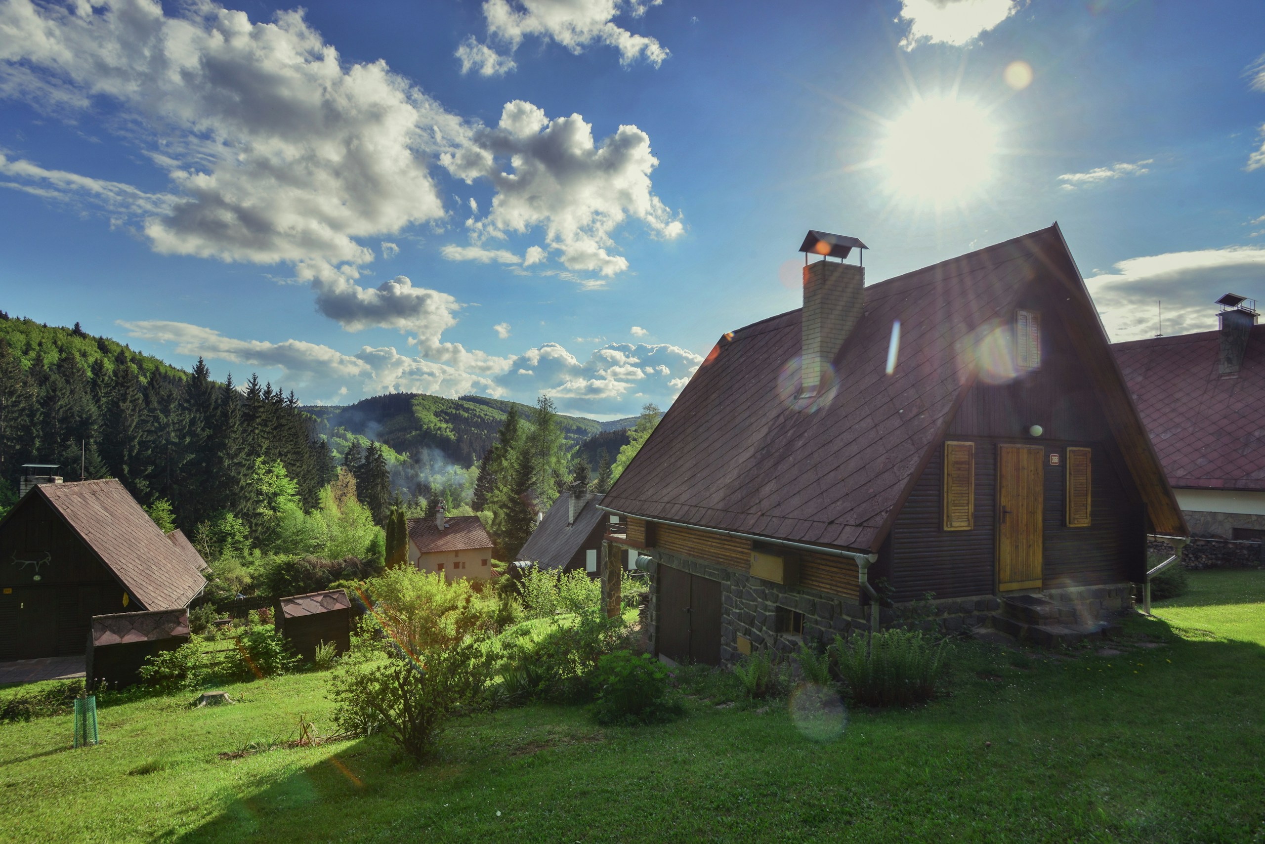 Wooden cabins on a grassy hill under a sunny sky HD Wallpaper