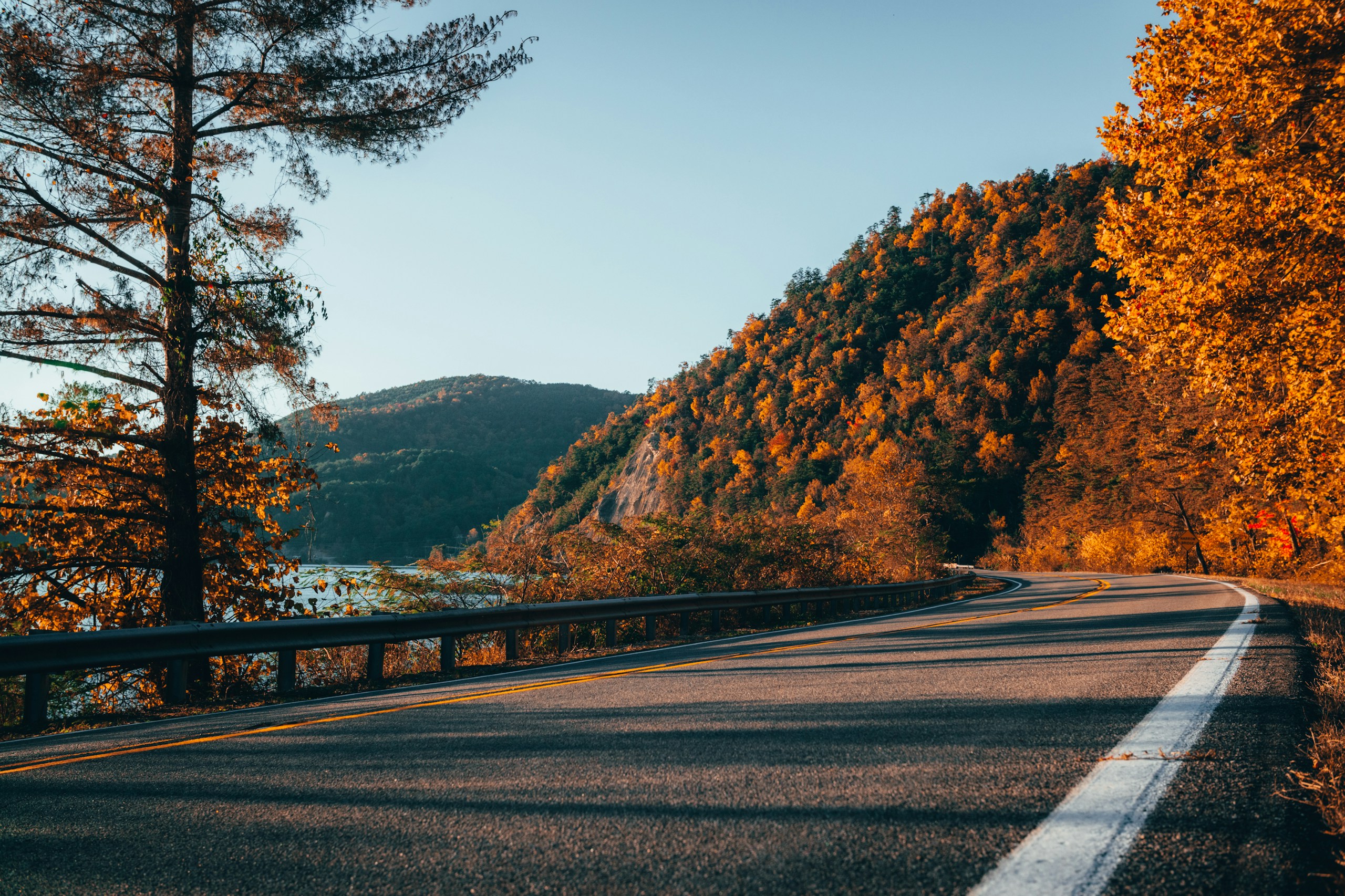Winding asphalt road next to autumn forest and mountains HD Wallpaper