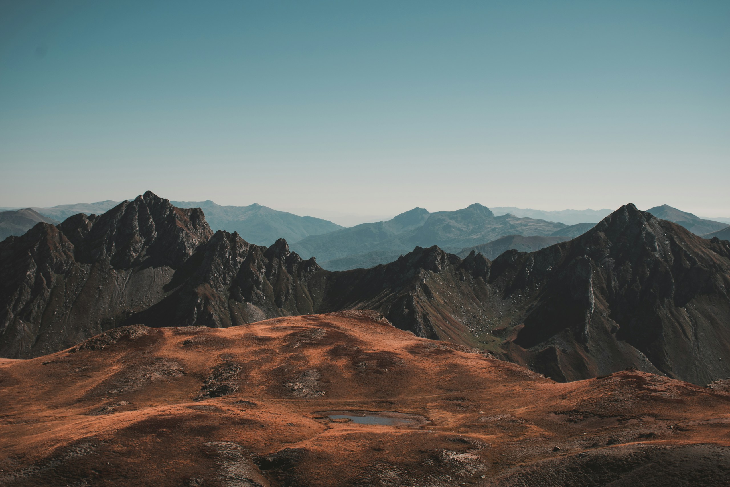 Mountain range with a small lake in the foreground HD Wallpaper