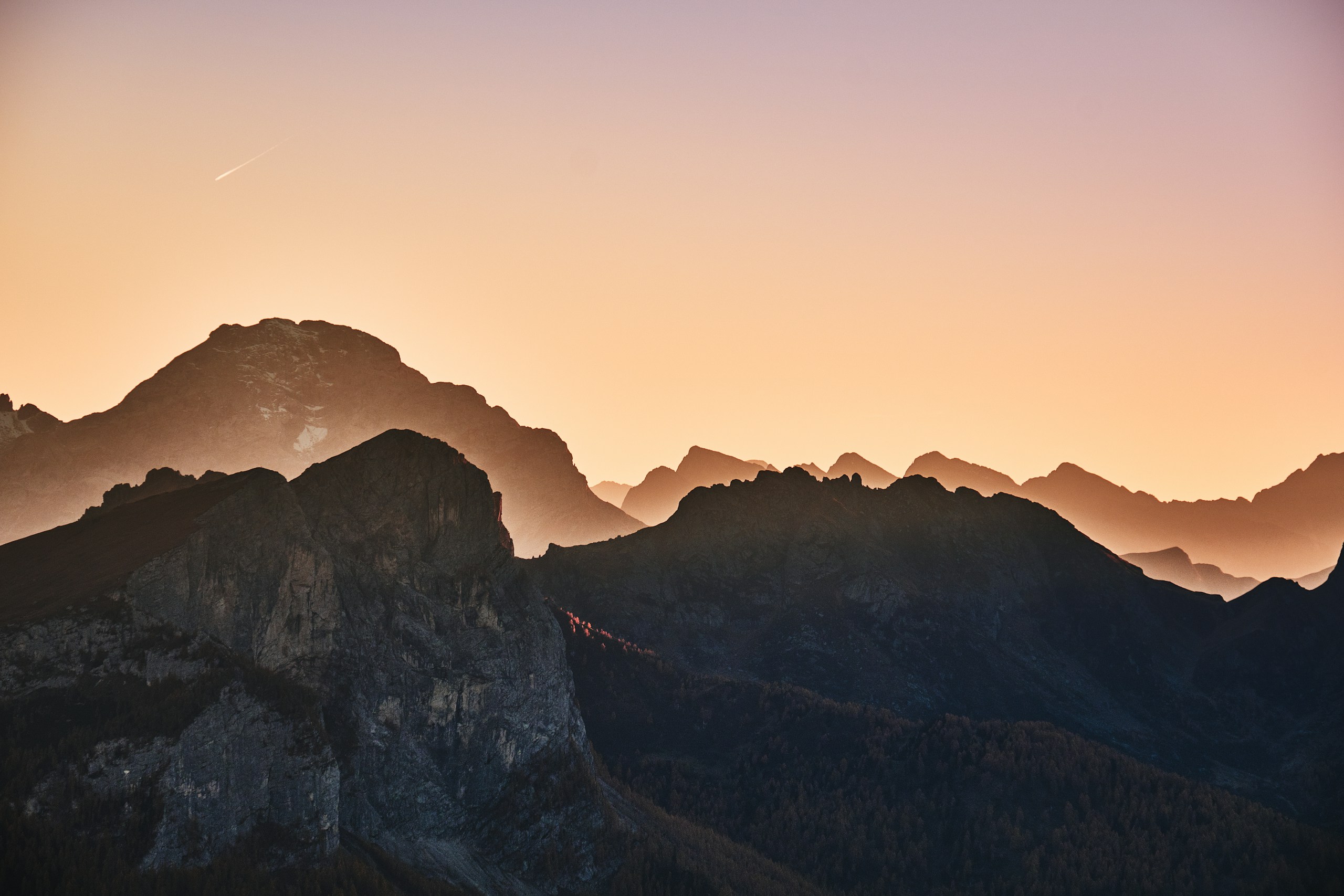 Rocky mountain peaks silhouetted against a sunset sky HD Wallpaper