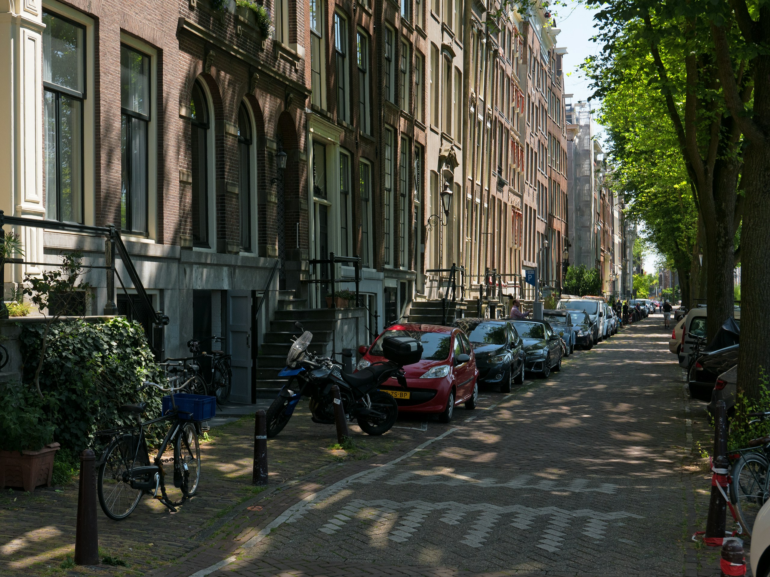 Historic street in Amsterdam with parked vehicles HD Wallpaper