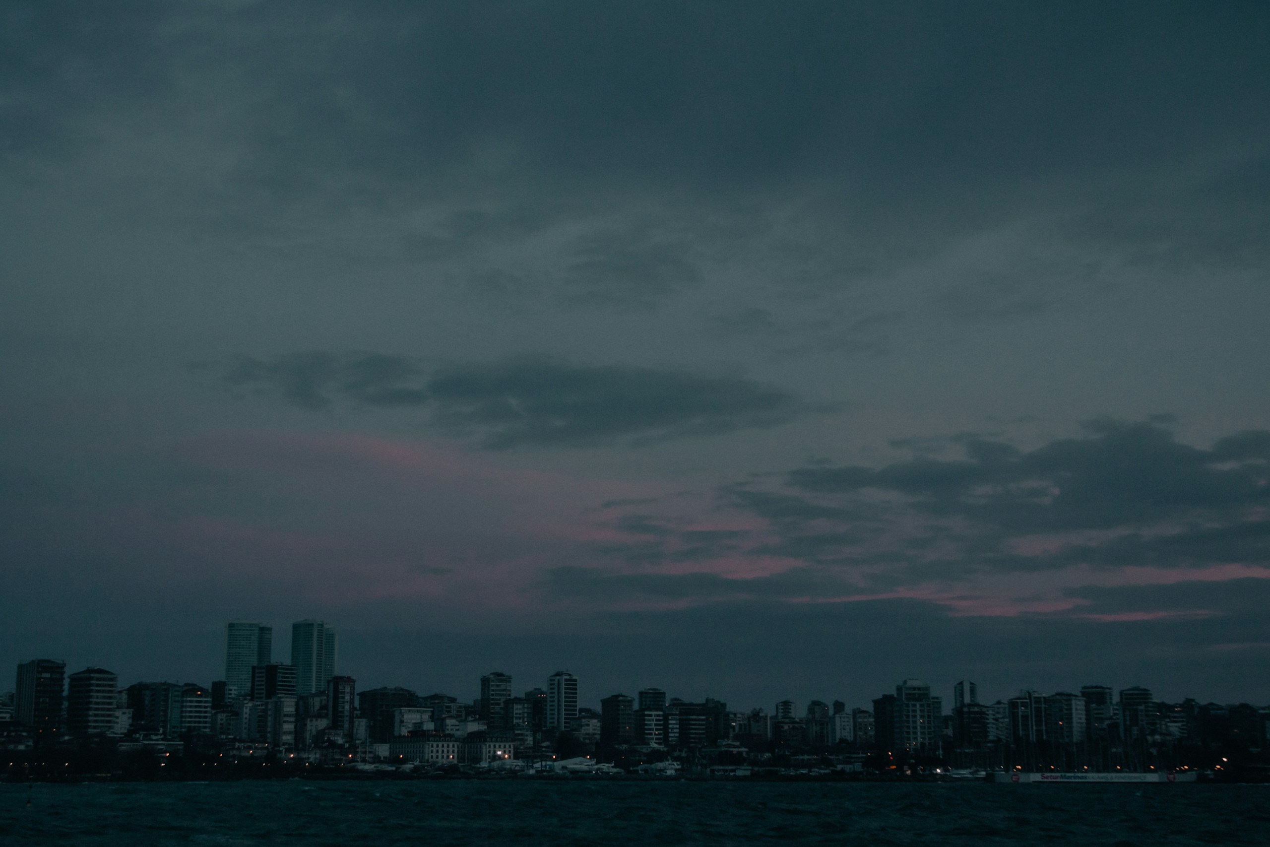 City skyline under dark cloudy sky at dusk HD Wallpaper