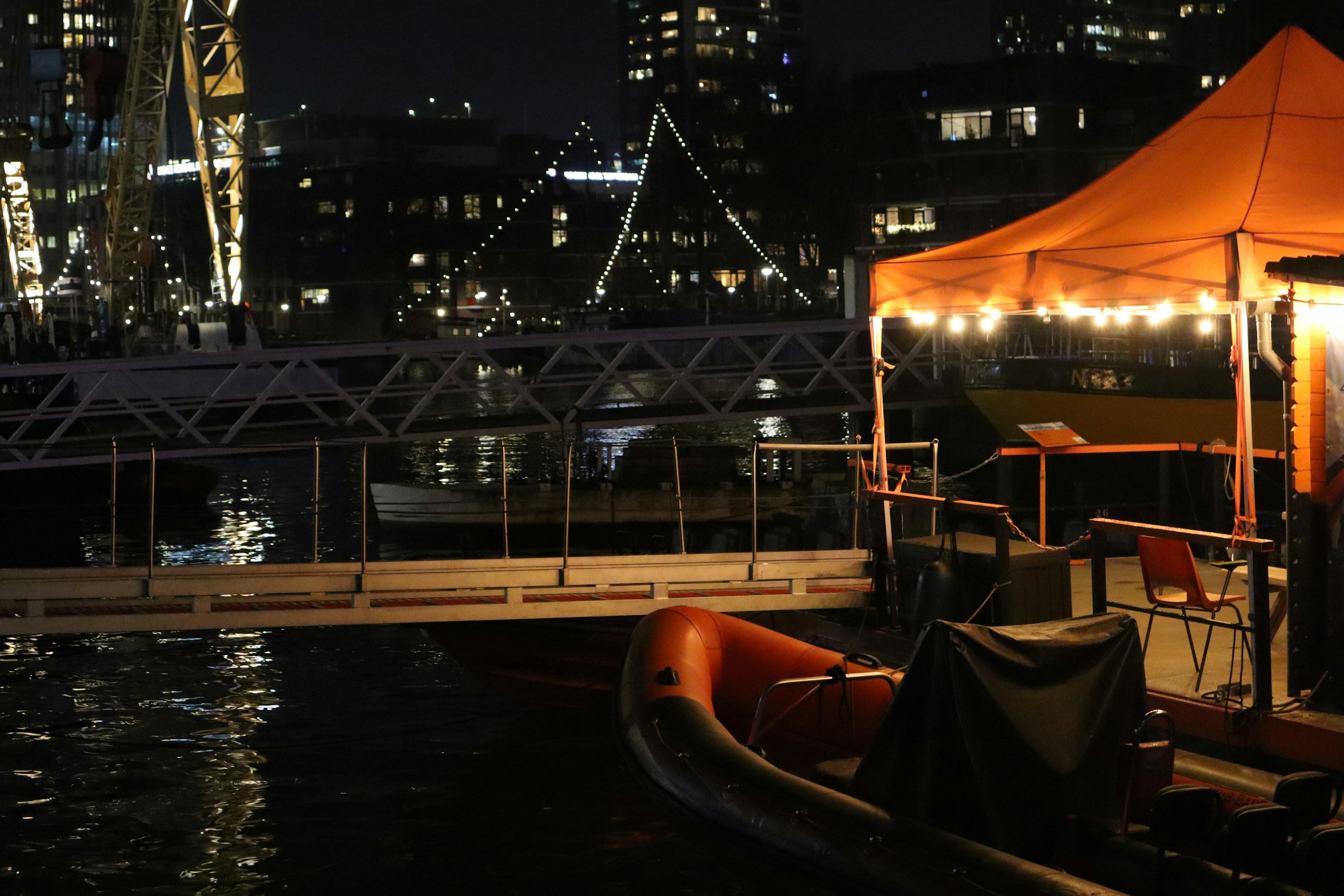 Night harbor scene with boat and illuminated orange tent HD Wallpaper