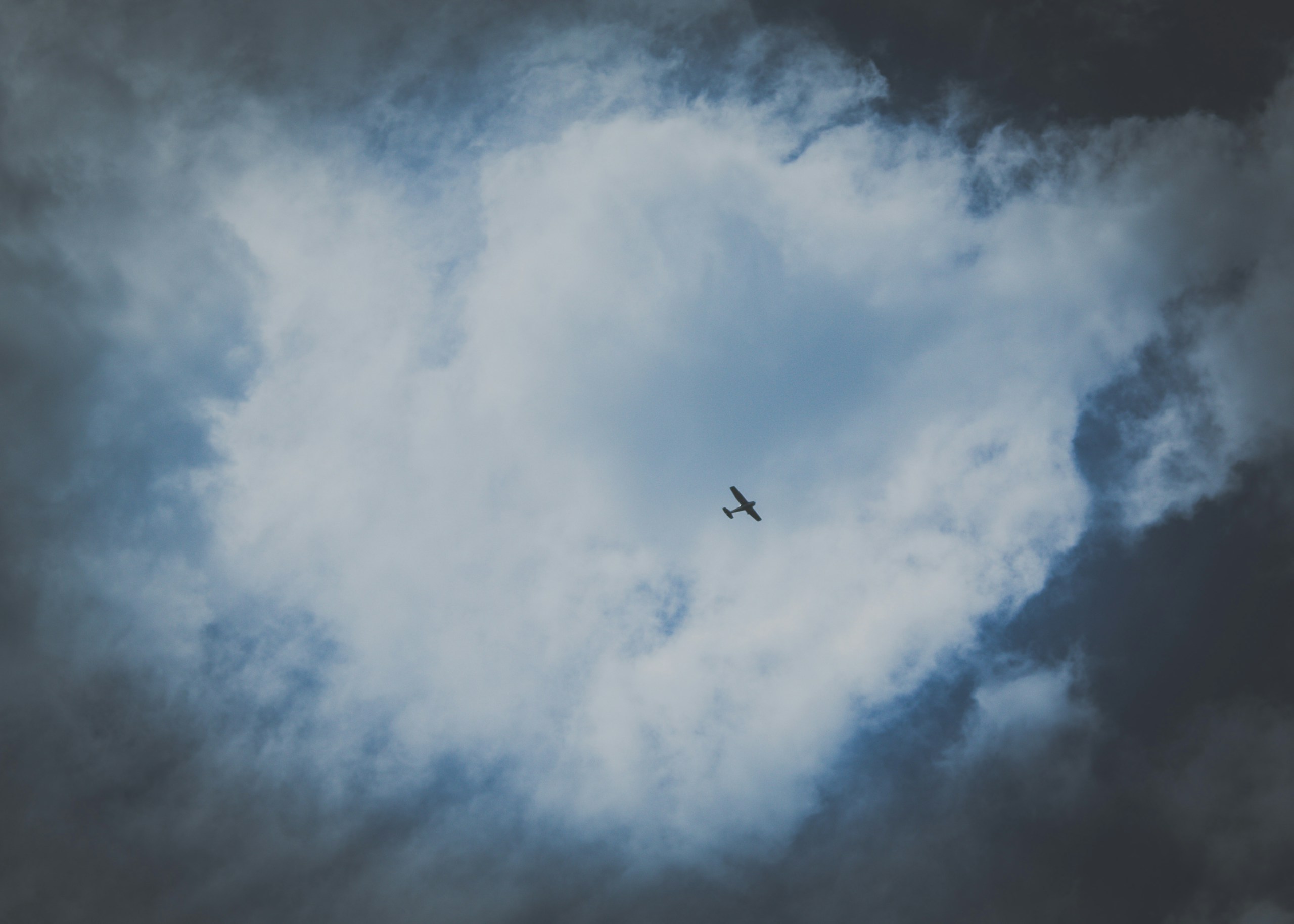 Small airplane flying through heart-shaped clouds HD Wallpaper