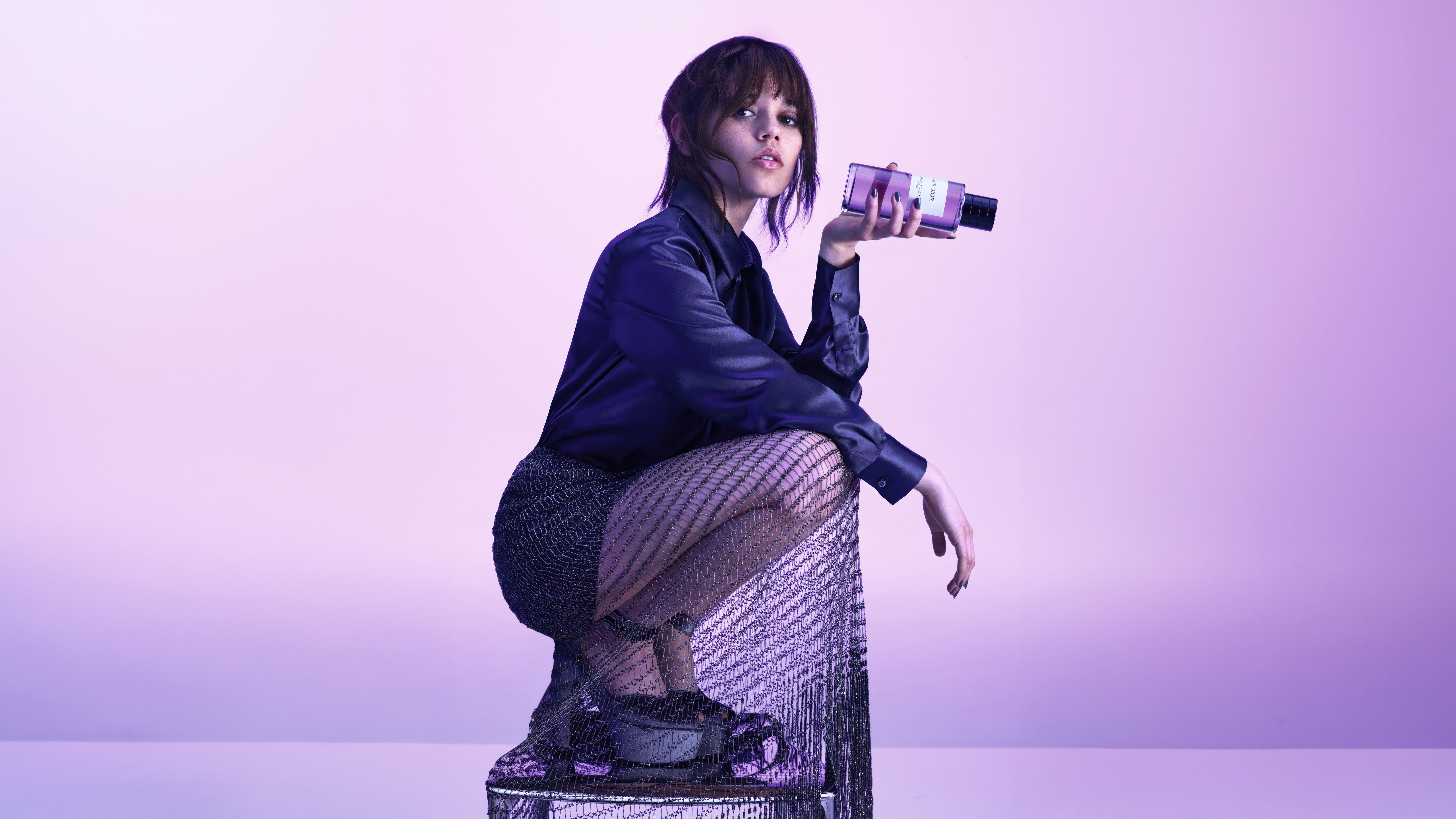 Jenna Ortega Crouching and Holding a Perfume Bottle HD Wallpaper