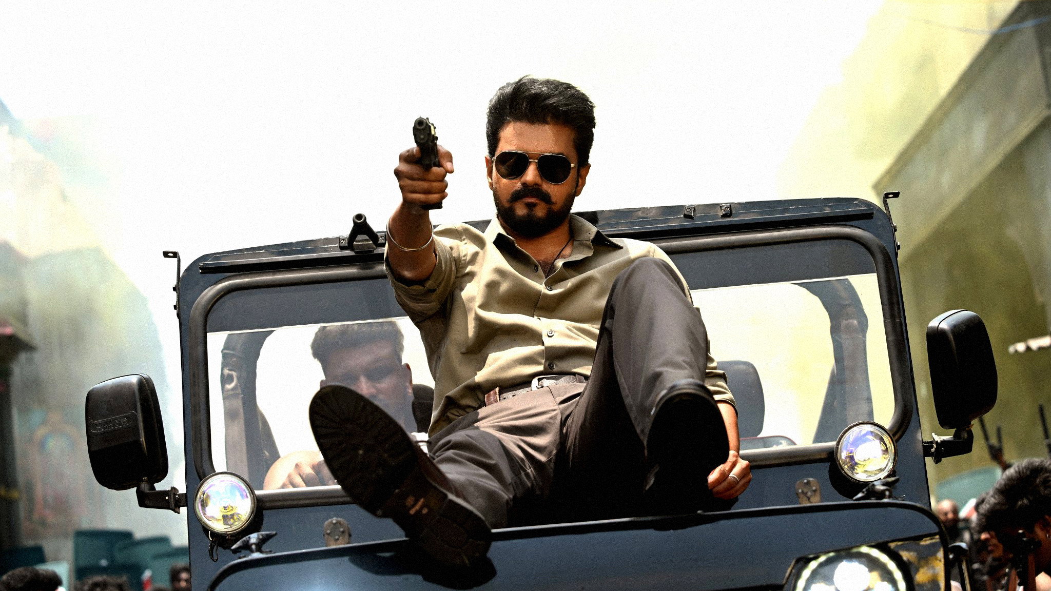 Actor Vijay pointing a gun from a jeep HD Wallpaper