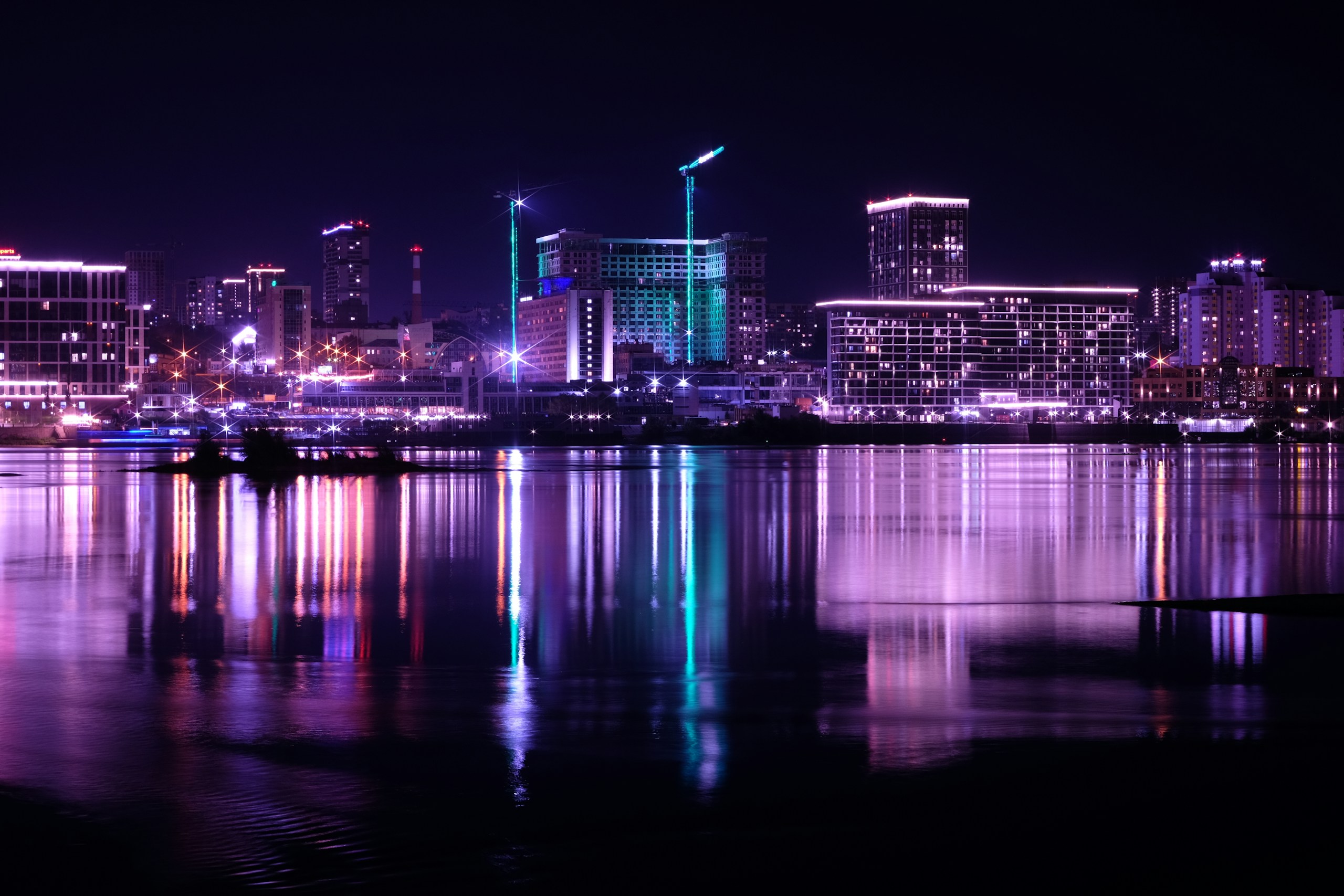 City skyline illuminated at night with water reflection HD Wallpaper