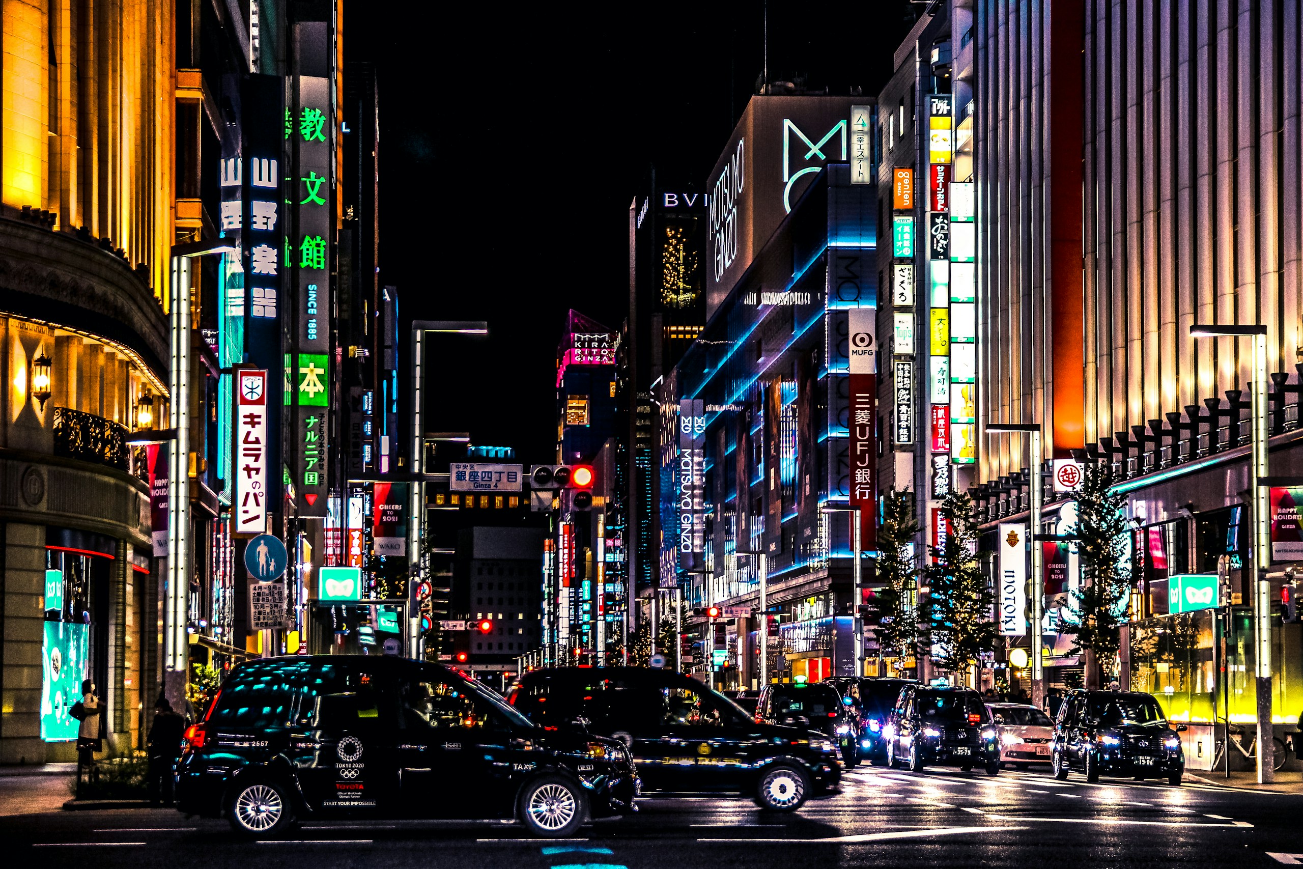 Tokyo street at night with neon signs and taxis HD Wallpaper