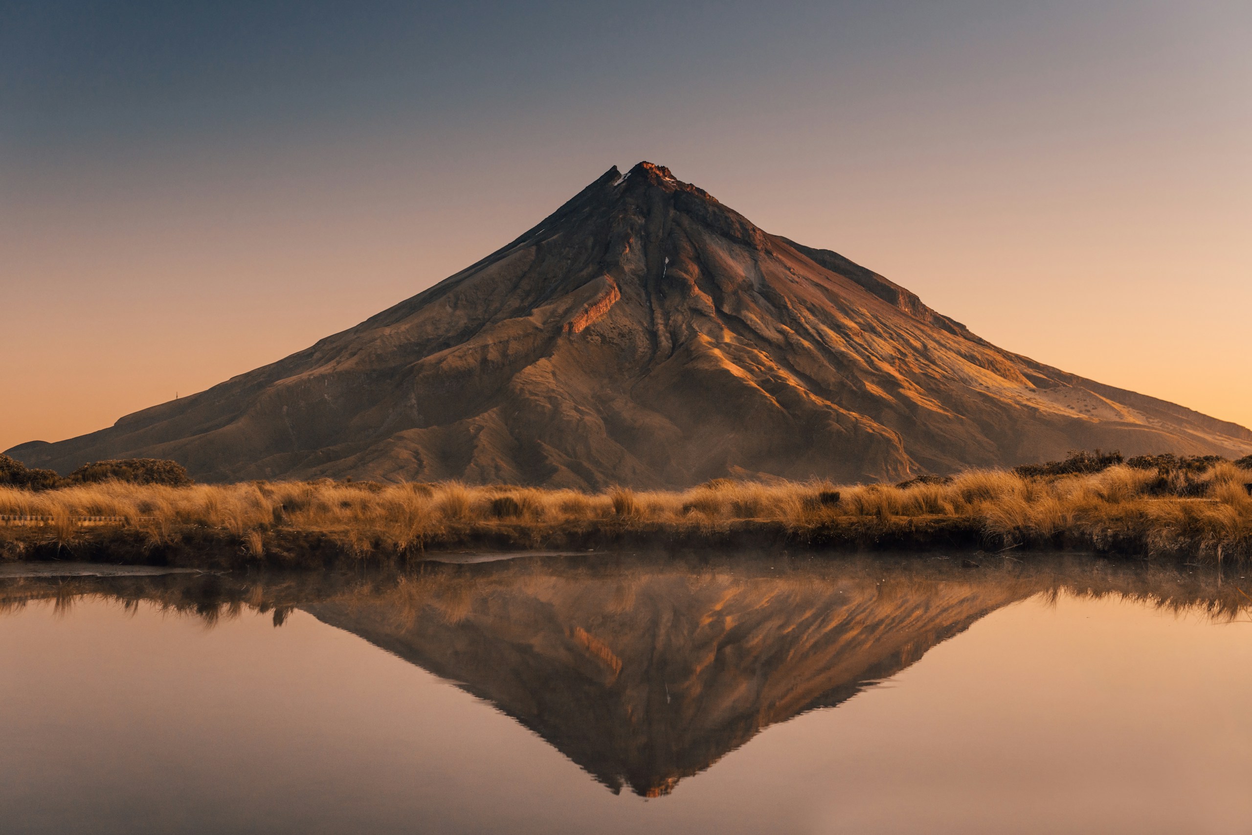 Volcano reflected in calm water at sunrise HD Wallpaper