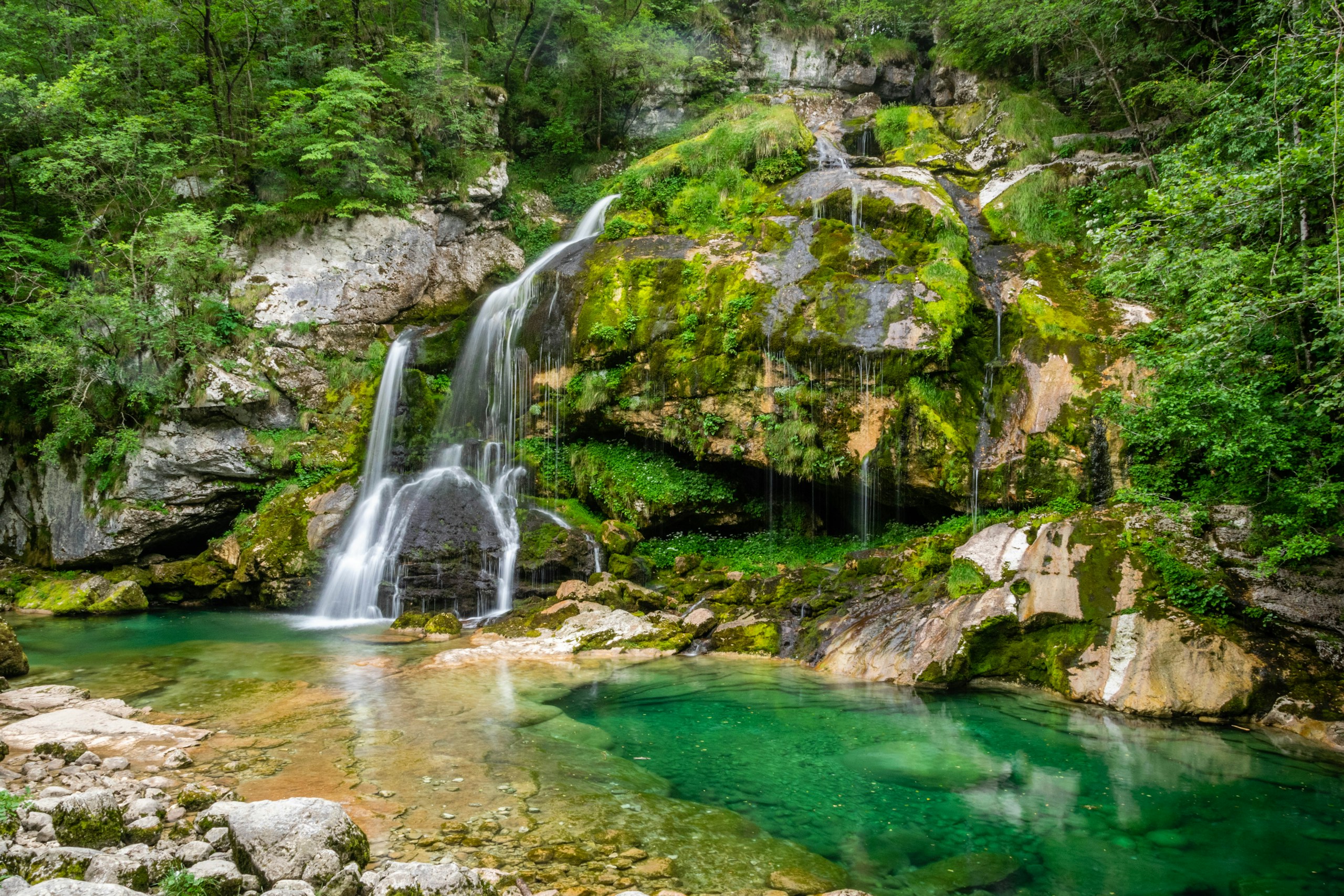 Waterfall cascading into a clear turquoise pool HD Wallpaper