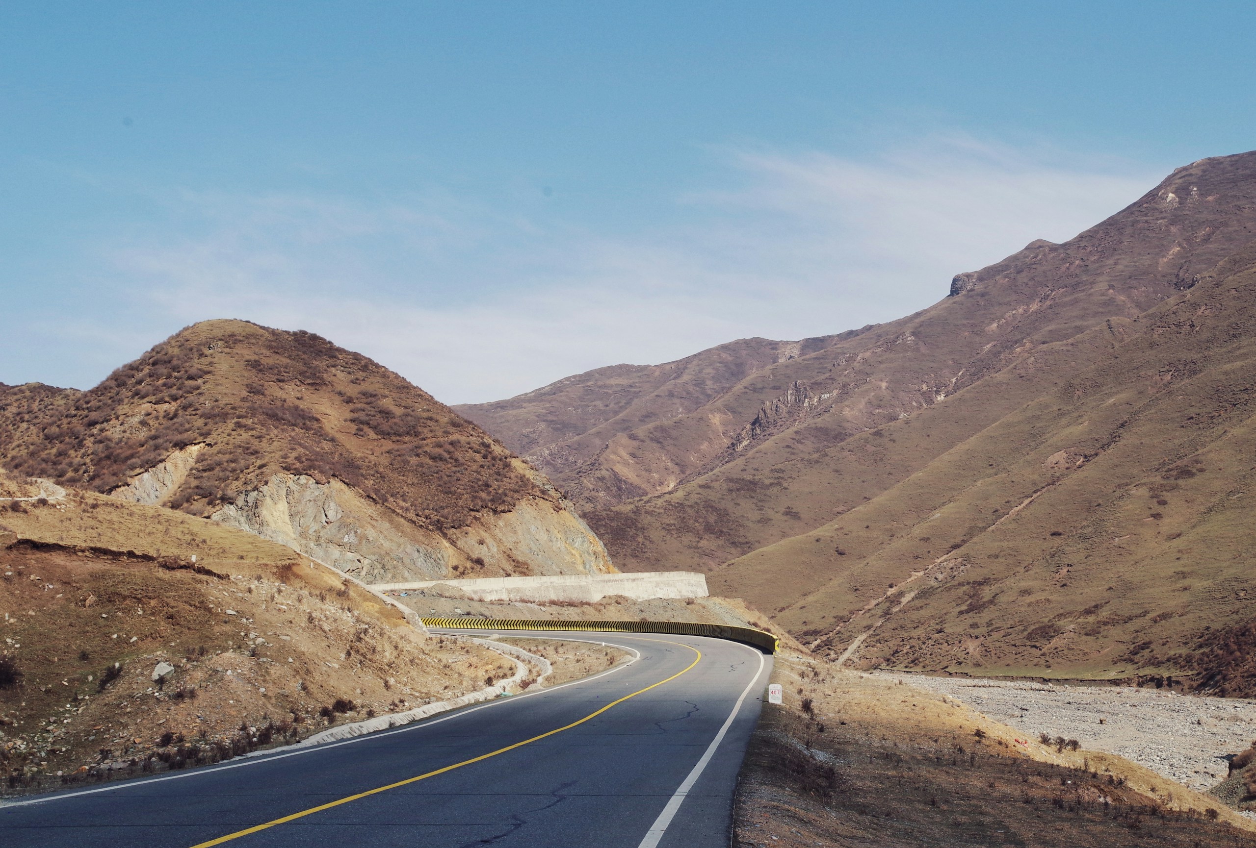 Winding mountain road under a clear blue sky HD Wallpaper