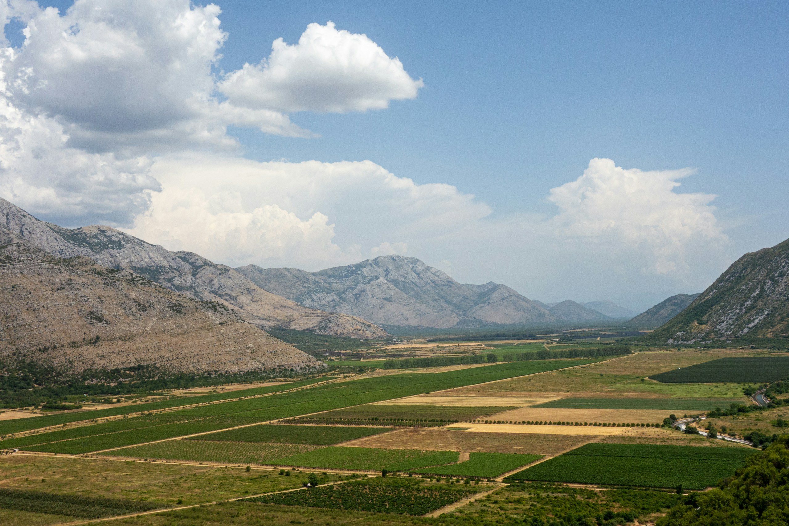 Agricultural fields in a valley with mountains HD Wallpaper
