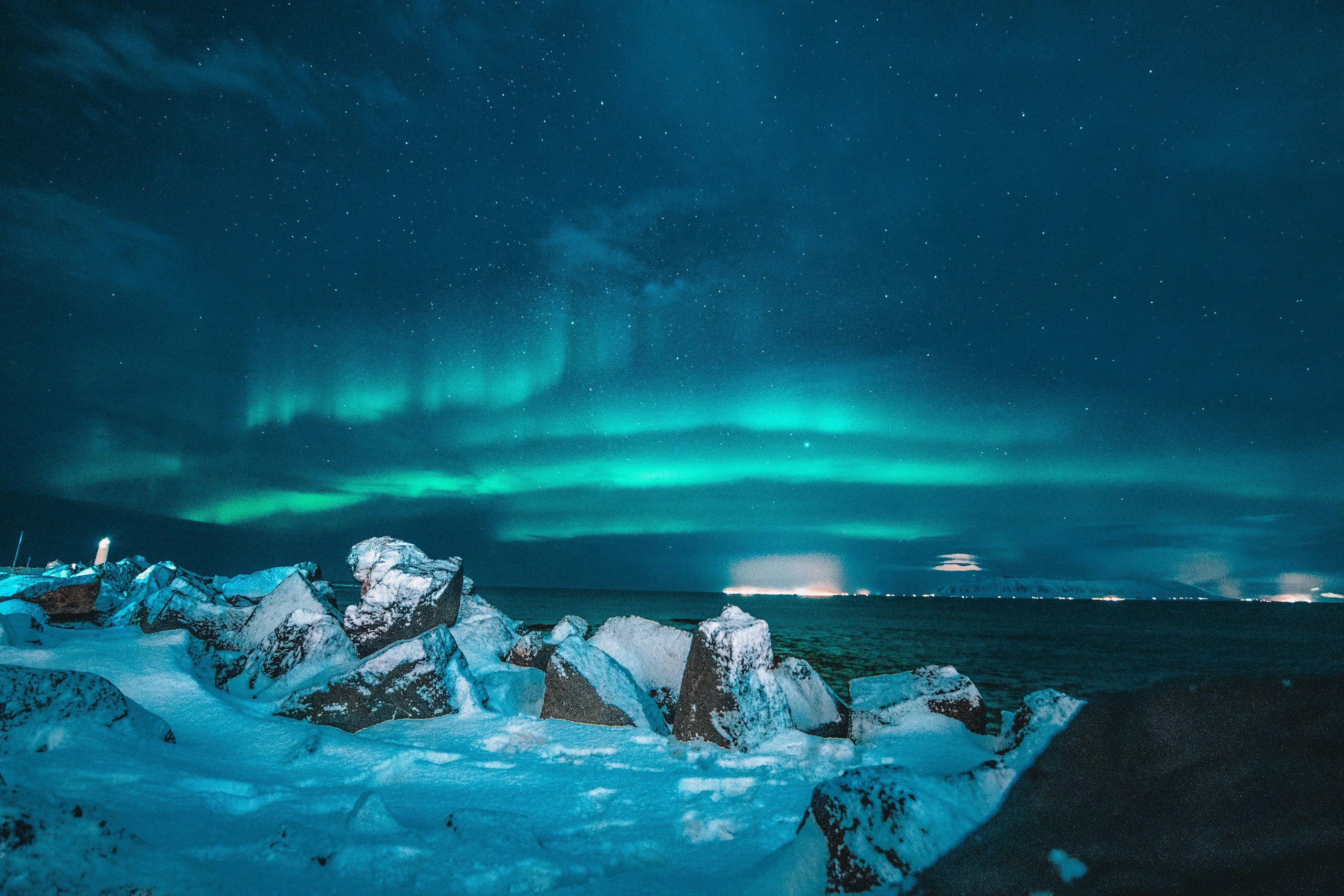 Aurora Borealis over snowy rocks and ocean HD Wallpaper