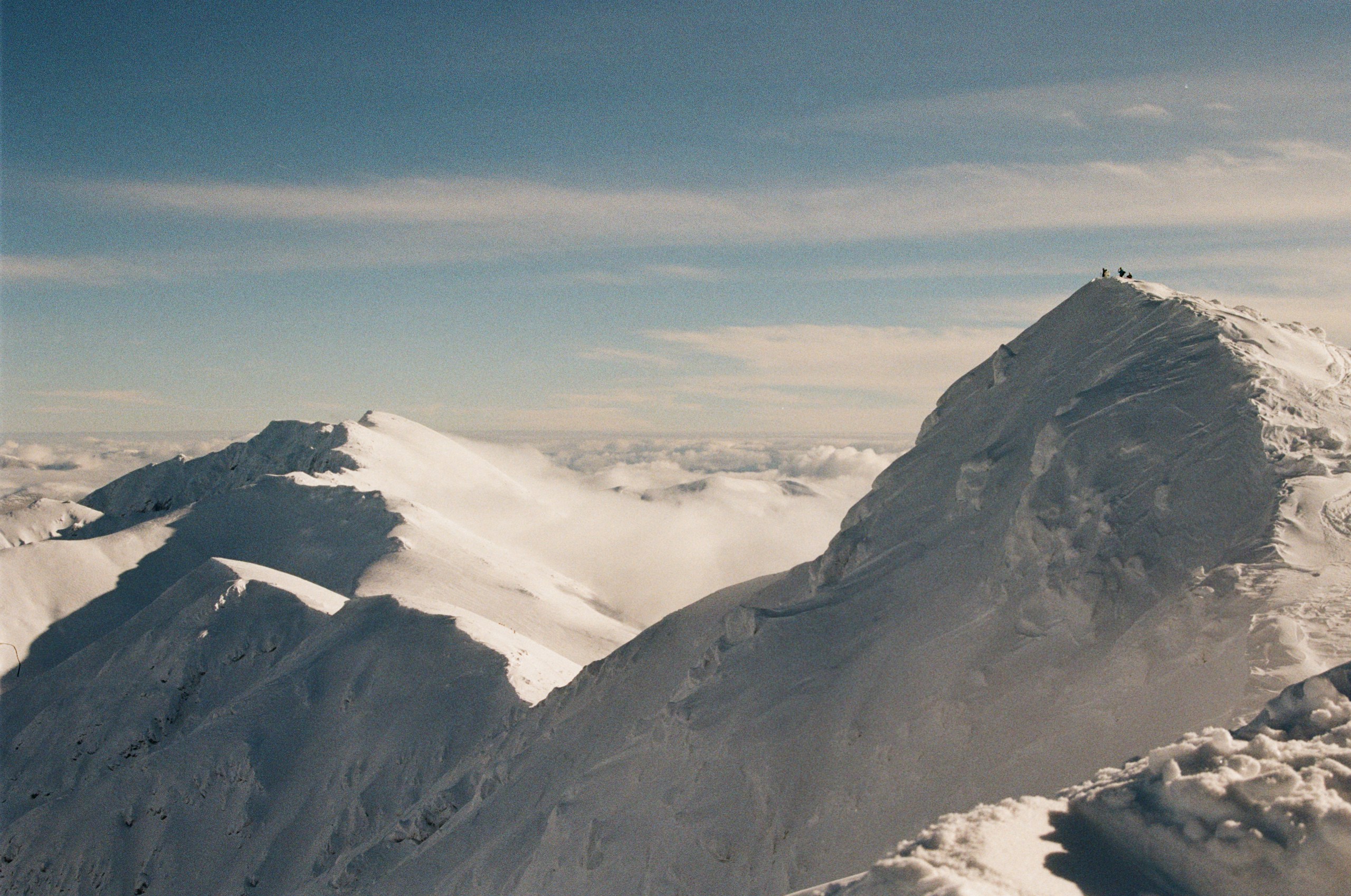 Snowy mountain peaks with tiny figures on summit HD Wallpaper