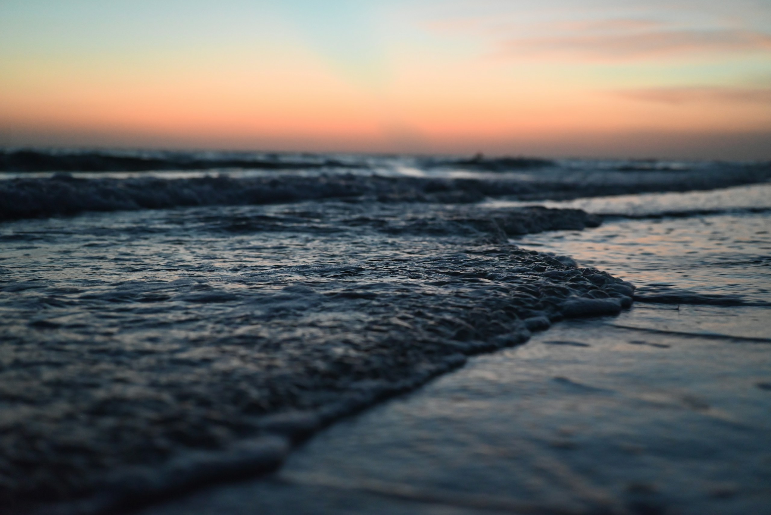 Gentle waves lap the shore at sunset HD Wallpaper