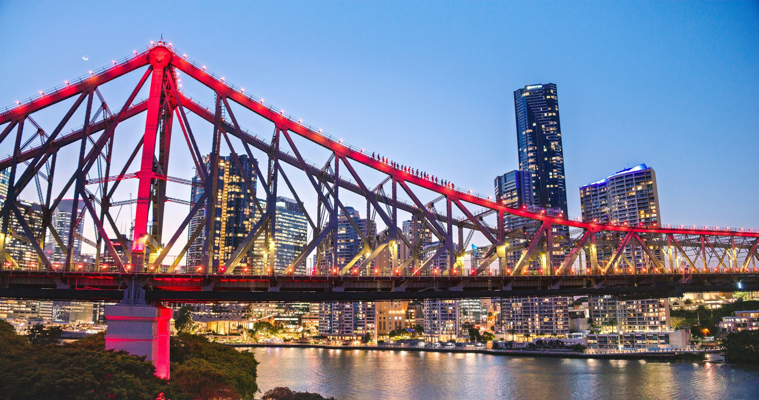 Story Bridge illuminated red at night with city skyline HD Wallpaper