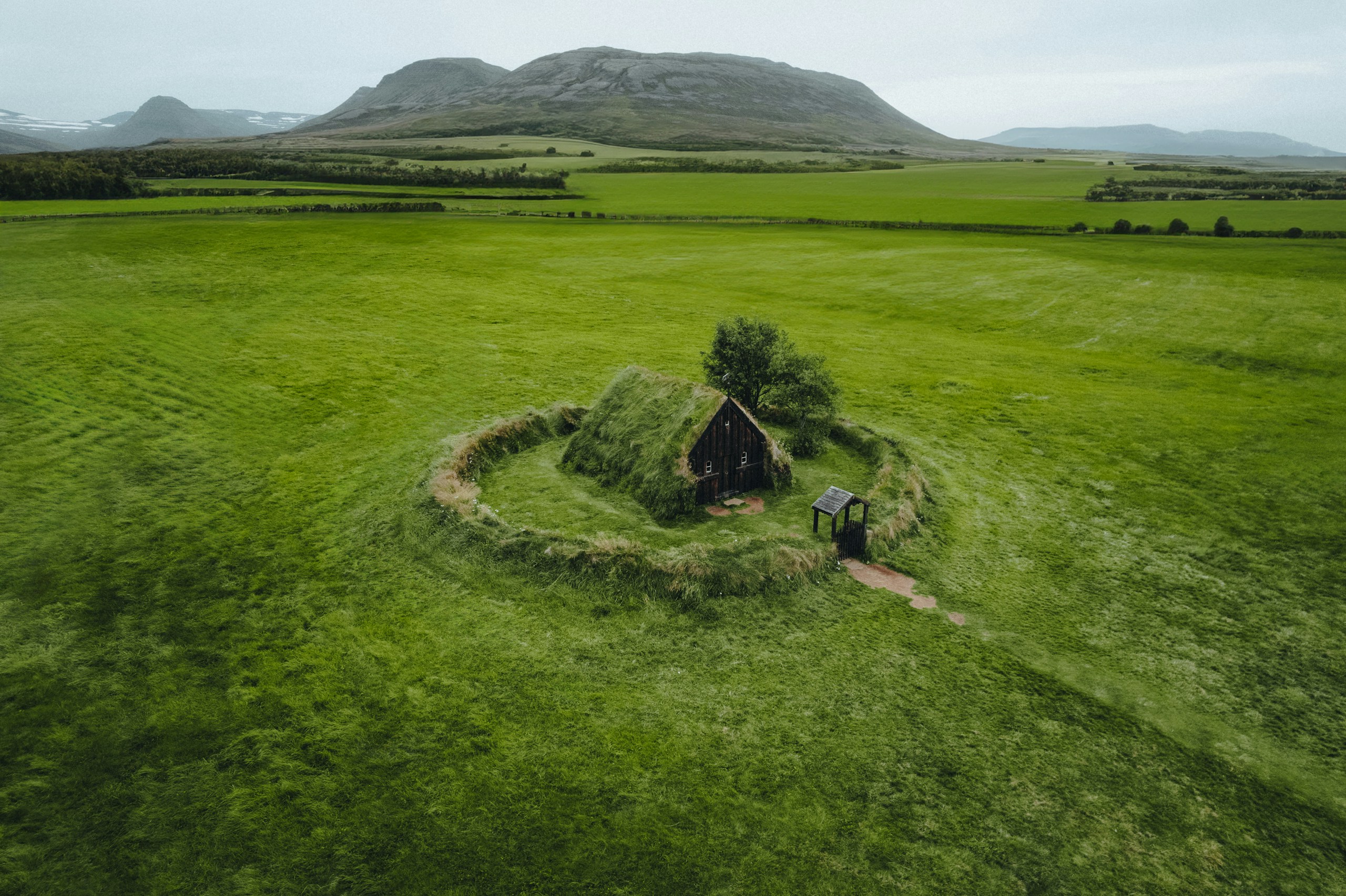 Small turf-roofed church in a green field HD Wallpaper