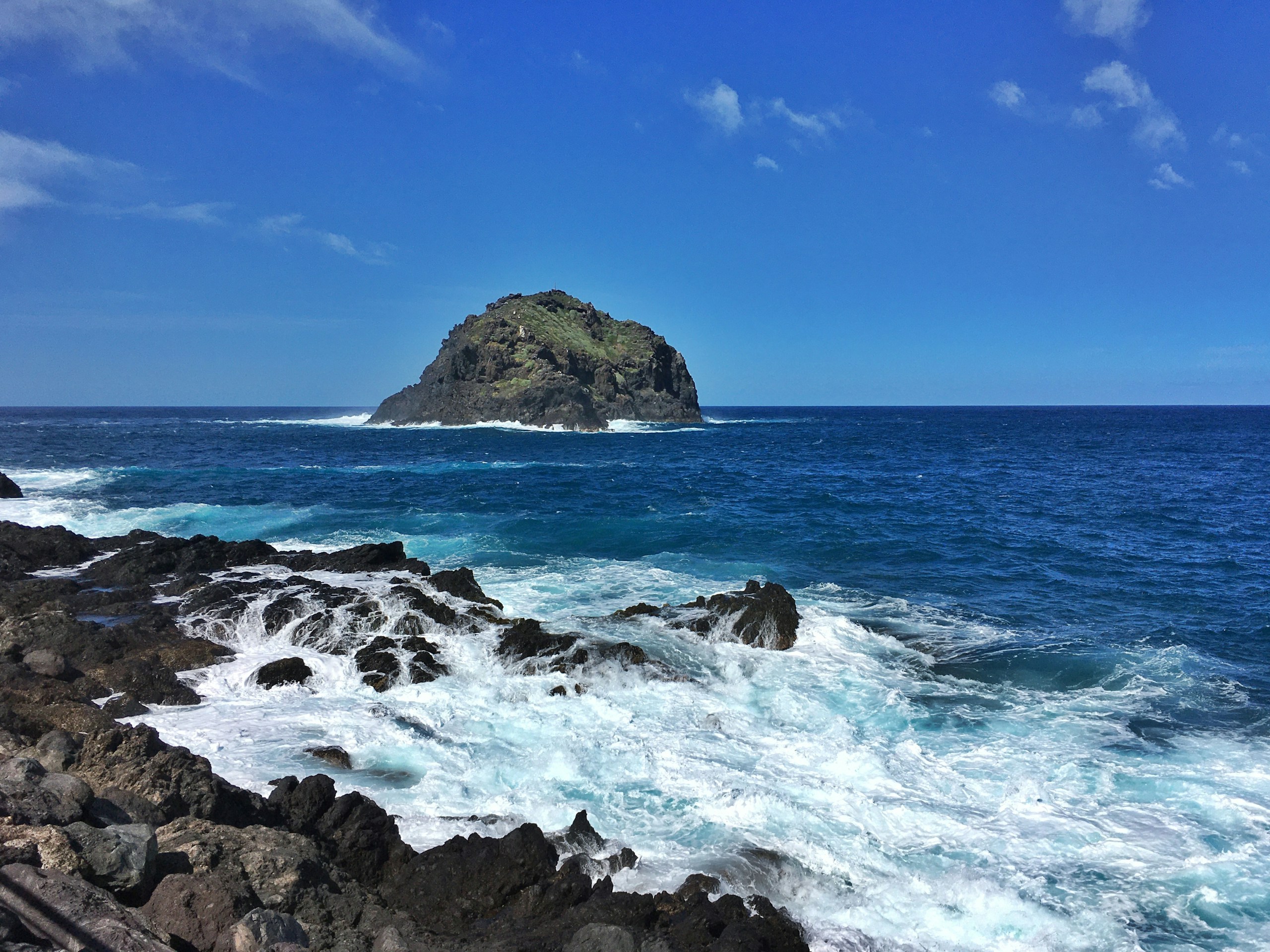 Rocky island in the ocean with waves crashing HD Wallpaper