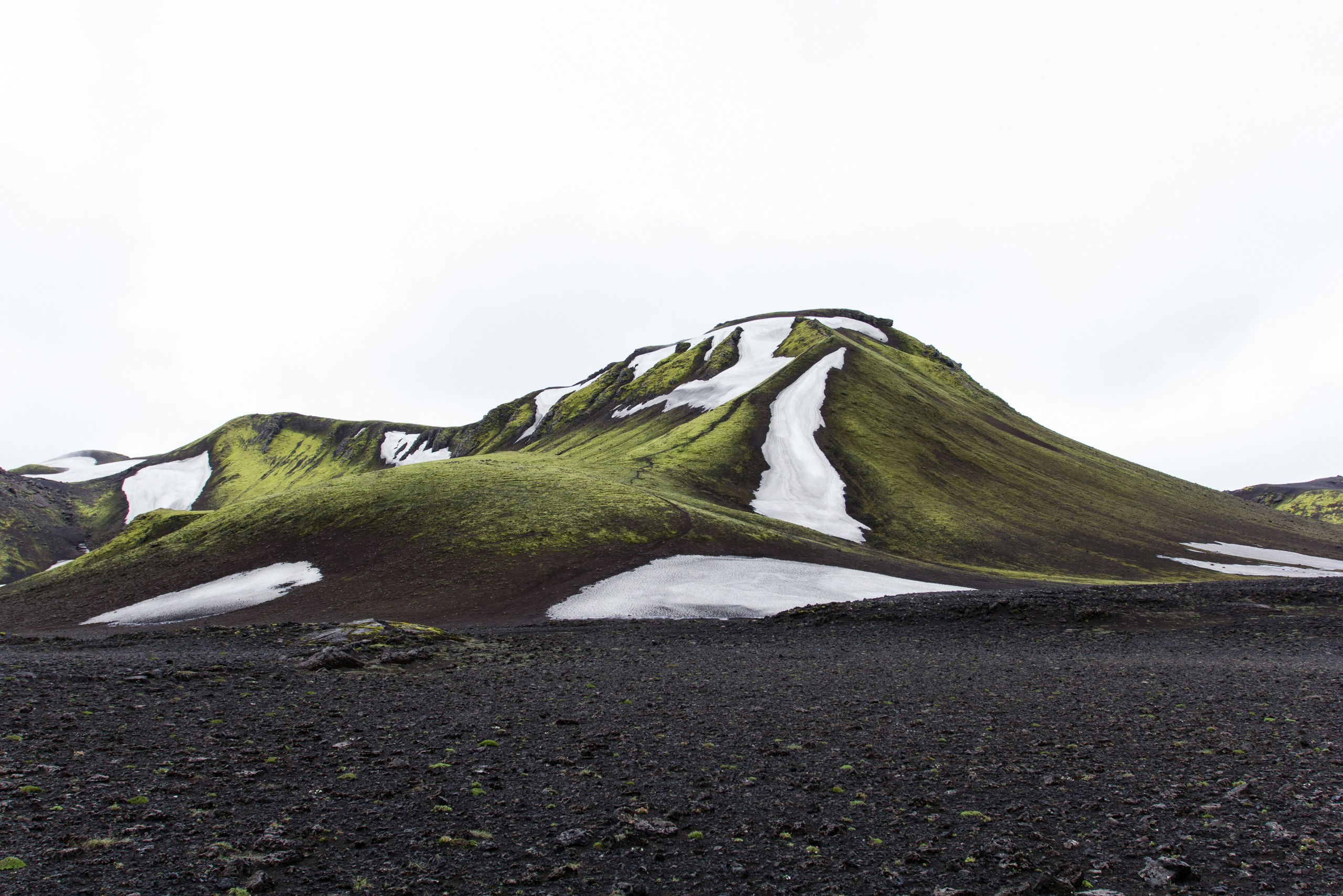Mossy mountain with snow patches and dark ground HD Wallpaper