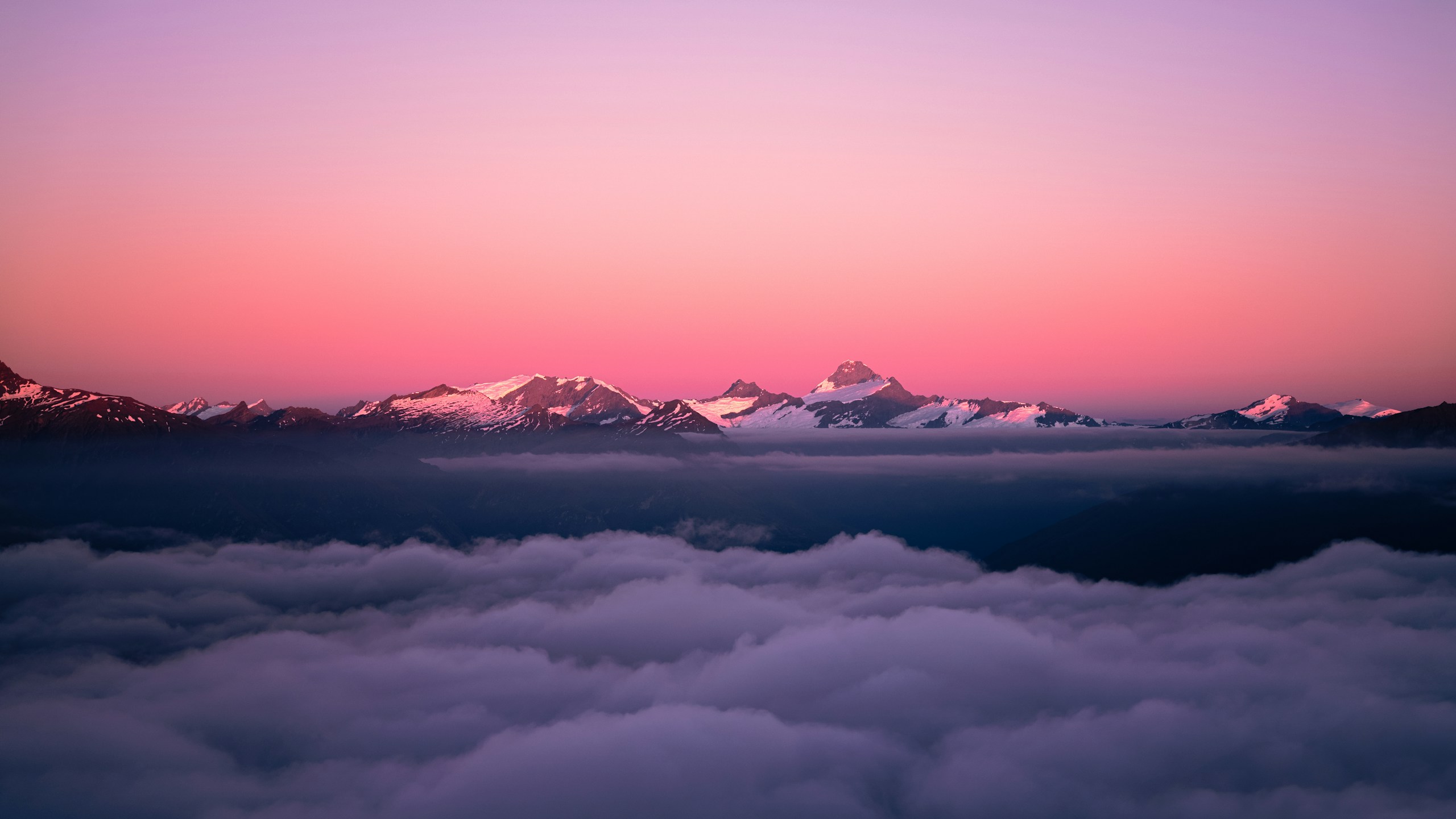 Snow-capped mountains above clouds at sunset HD Wallpaper