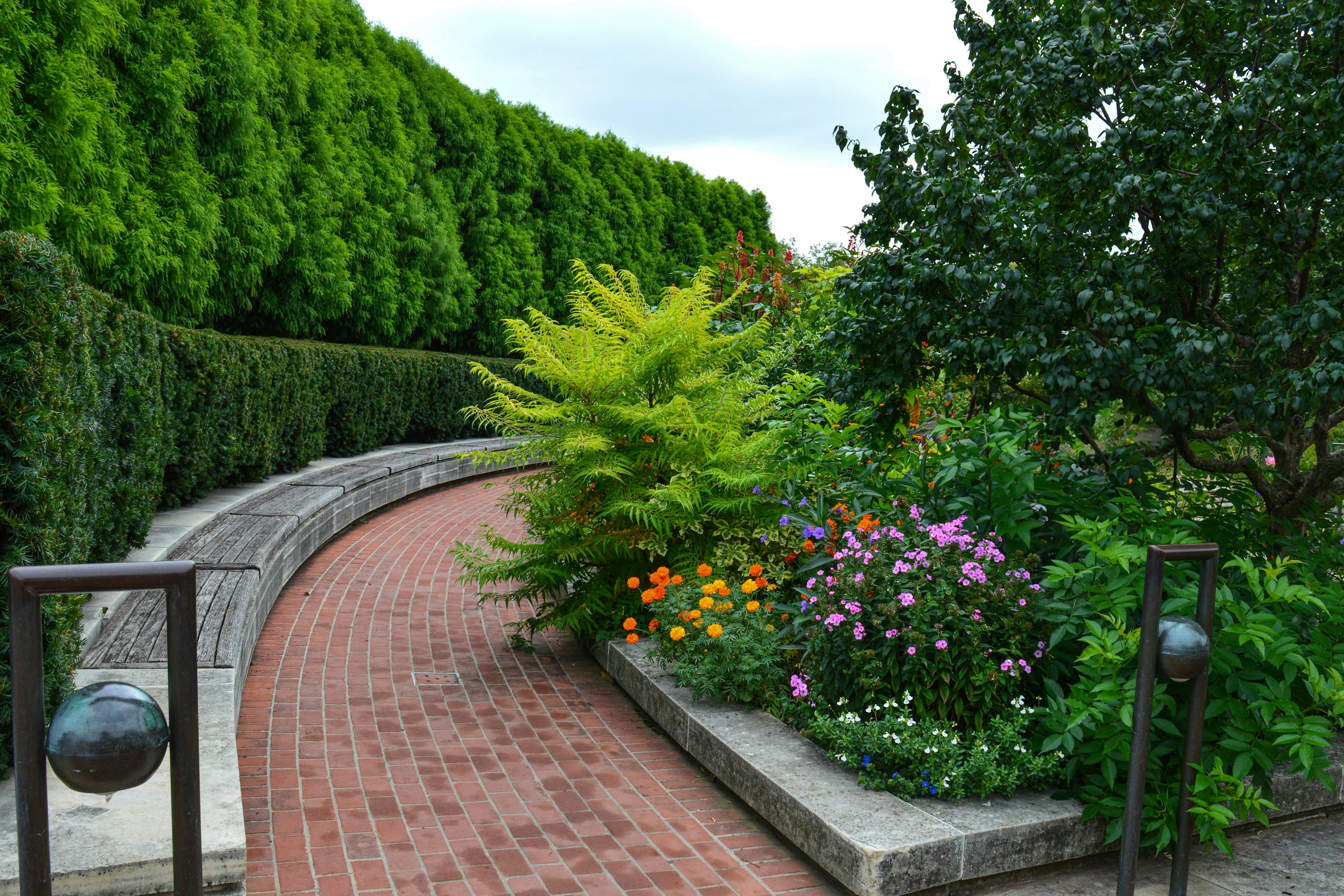 Curving brick path with lush garden and trees HD Wallpaper